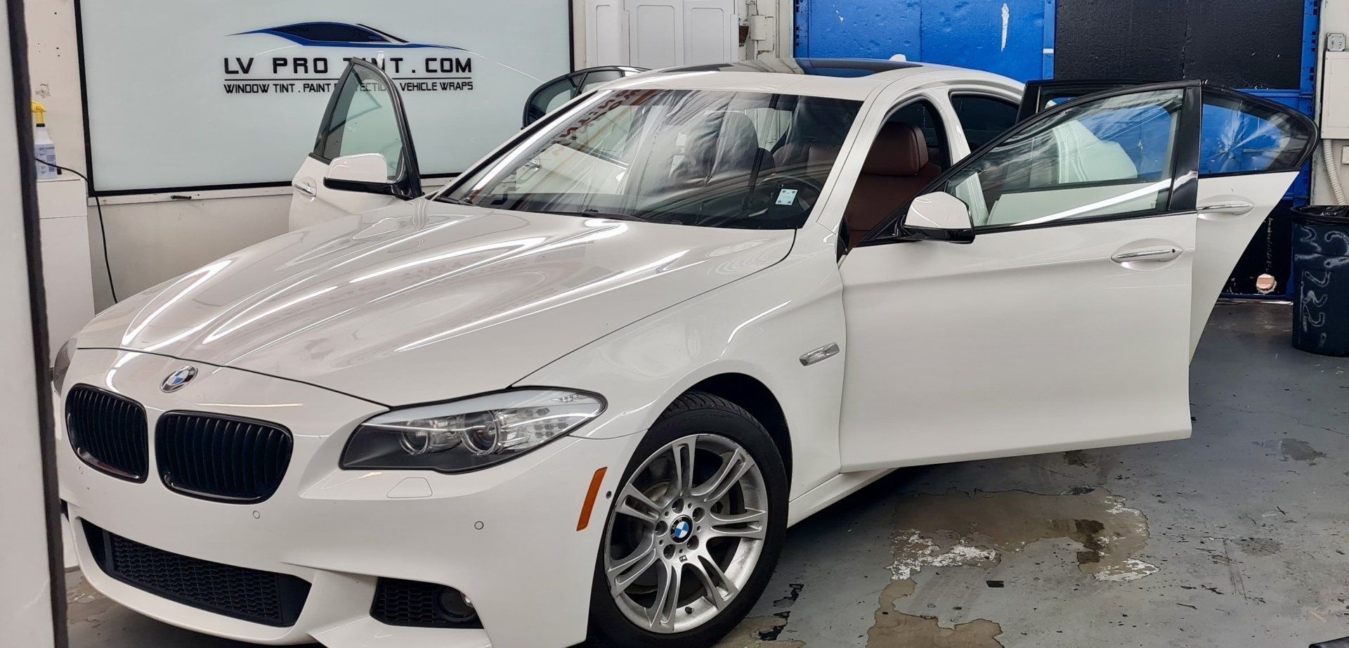 a white BMW is parked in a garage with its doors open.