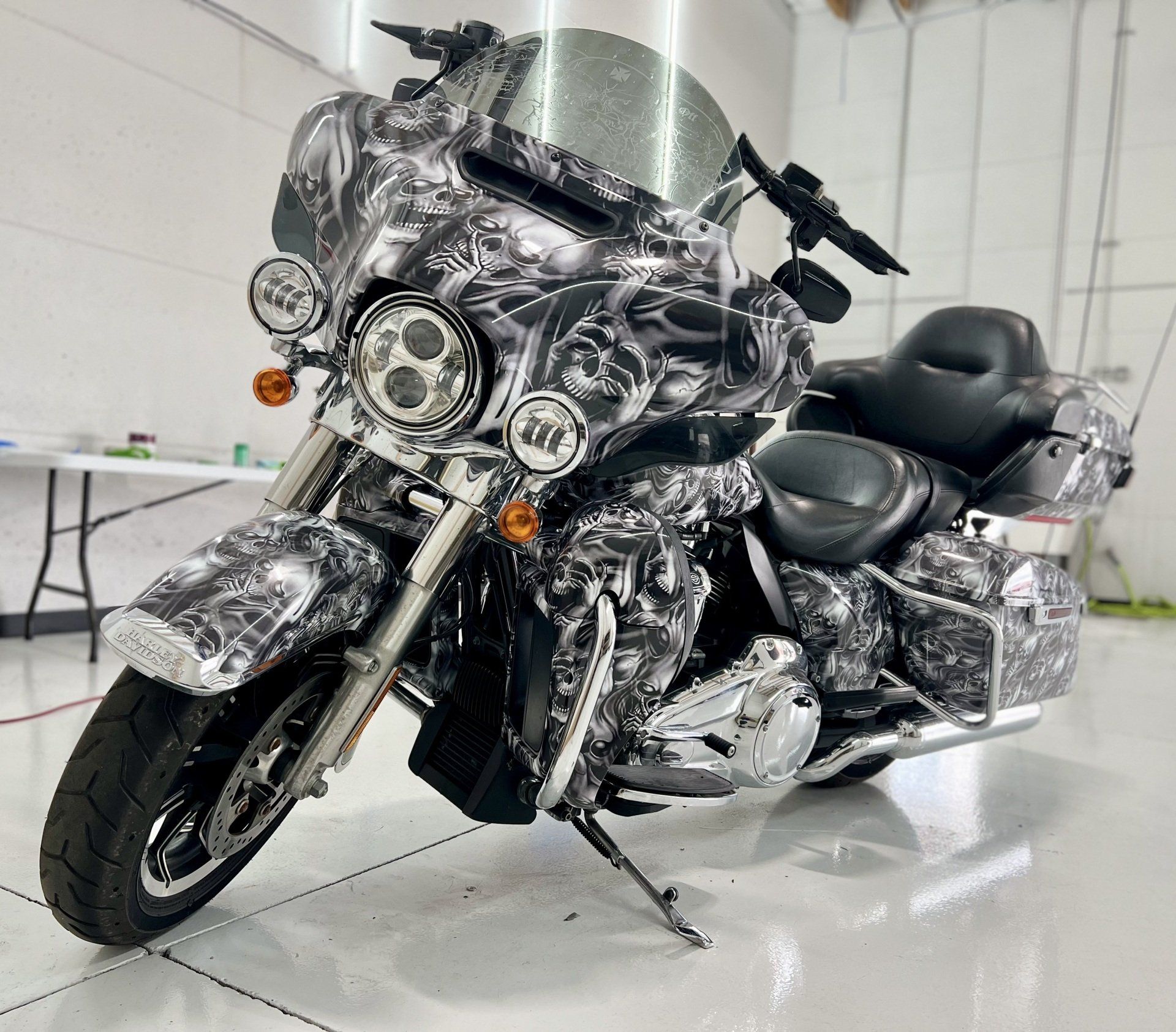 A Harley Davidson motorcycle with a camouflage paint job is parked in a garage.