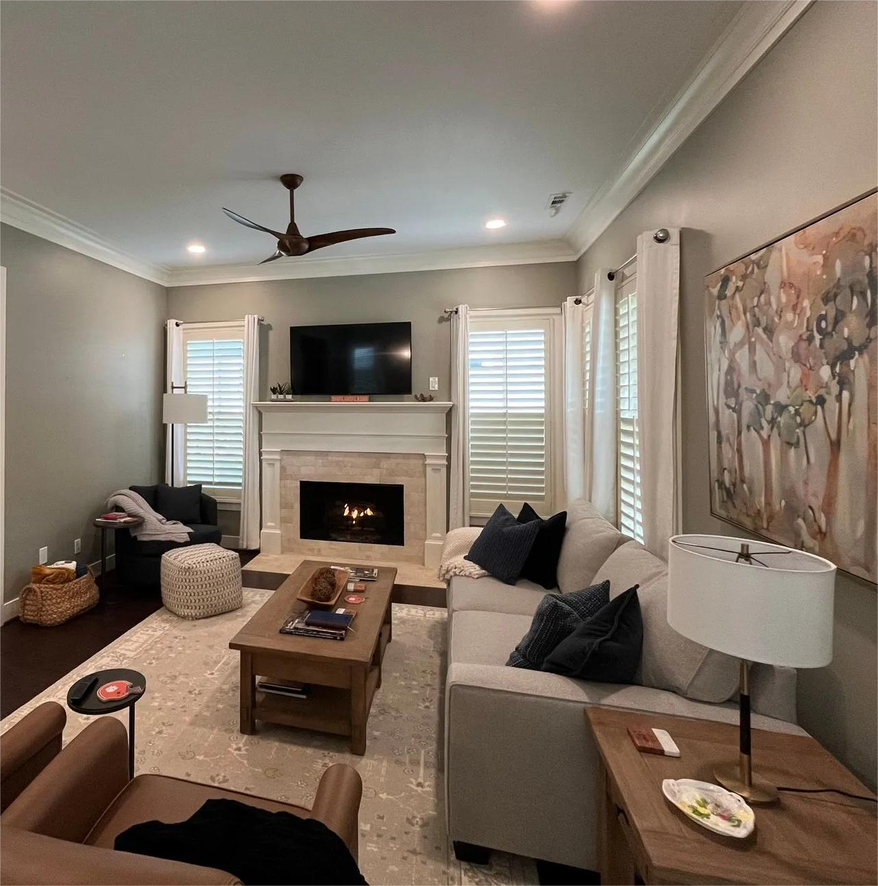 Living room with fireplace, sectional sofa, and artwork; neutral color palette.