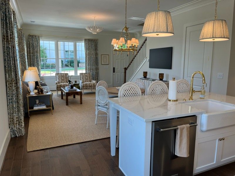 Open-concept living space with kitchen island, living room furniture, and a staircase leading upstairs.