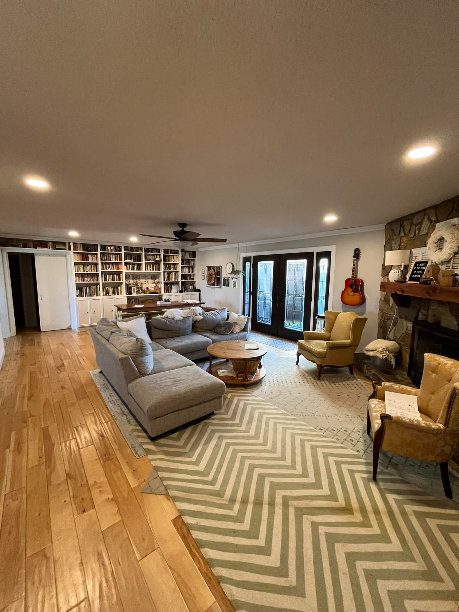 Living room with a gray sectional, rug, fireplace, bookshelves, and French doors.