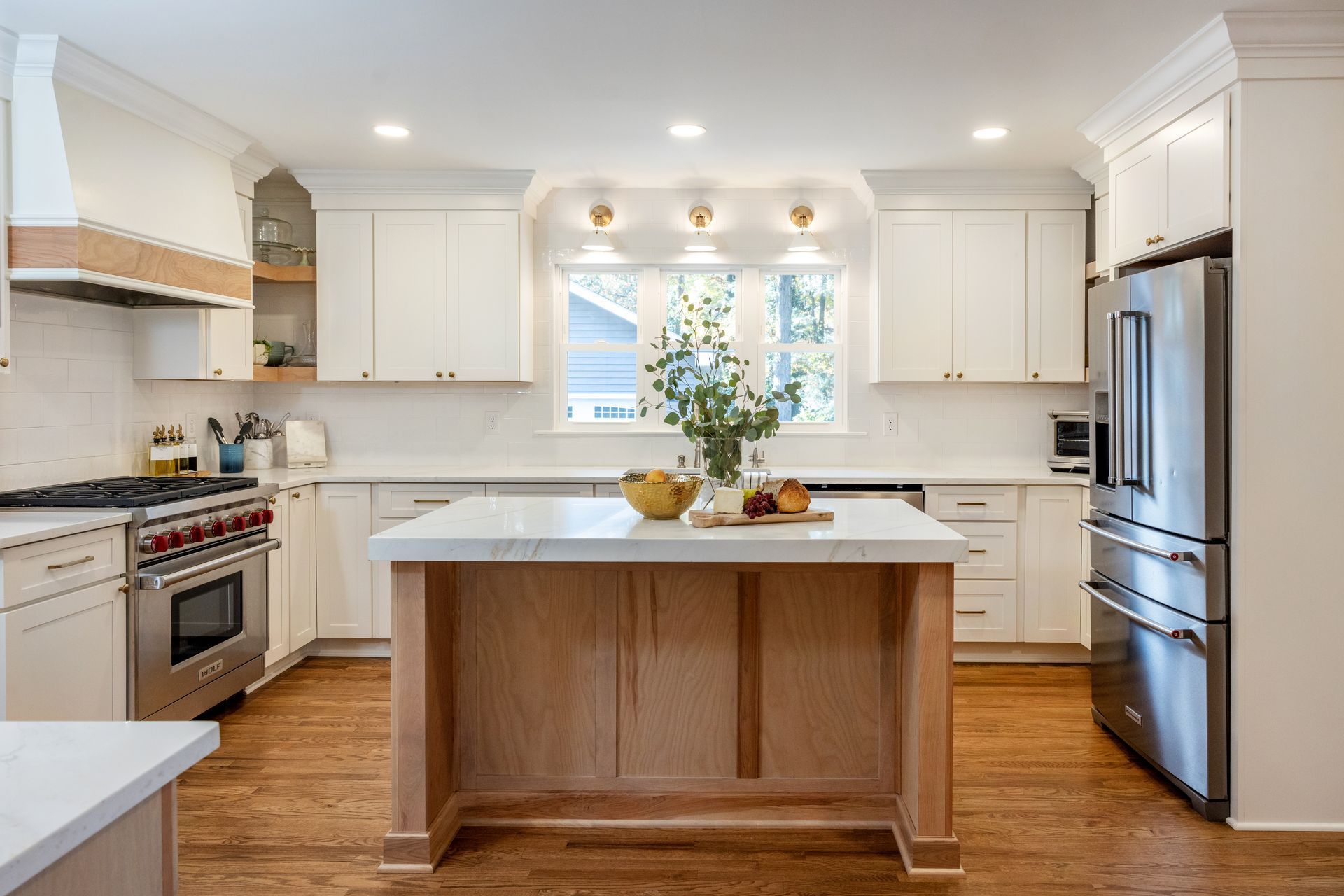Bright, remodeled kitchen with white cabinets, wood island, stainless steel appliances, and natural light.