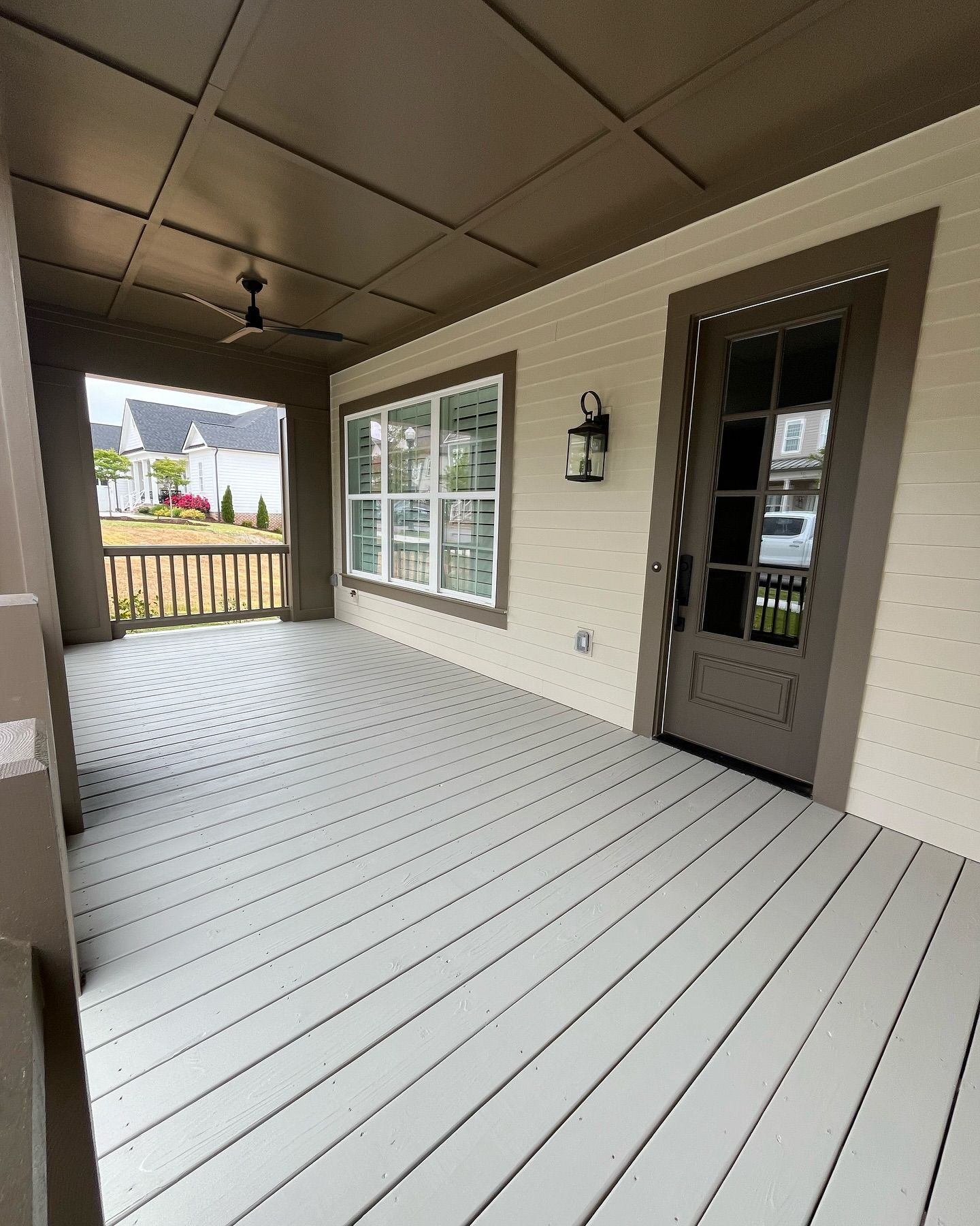 A gray-painted porch with a dark ceiling, door, and trim, white walls, and a view of the outside.