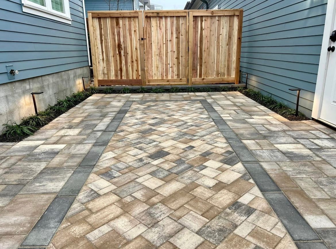 Wooden privacy fence along blue building next to paved patio.