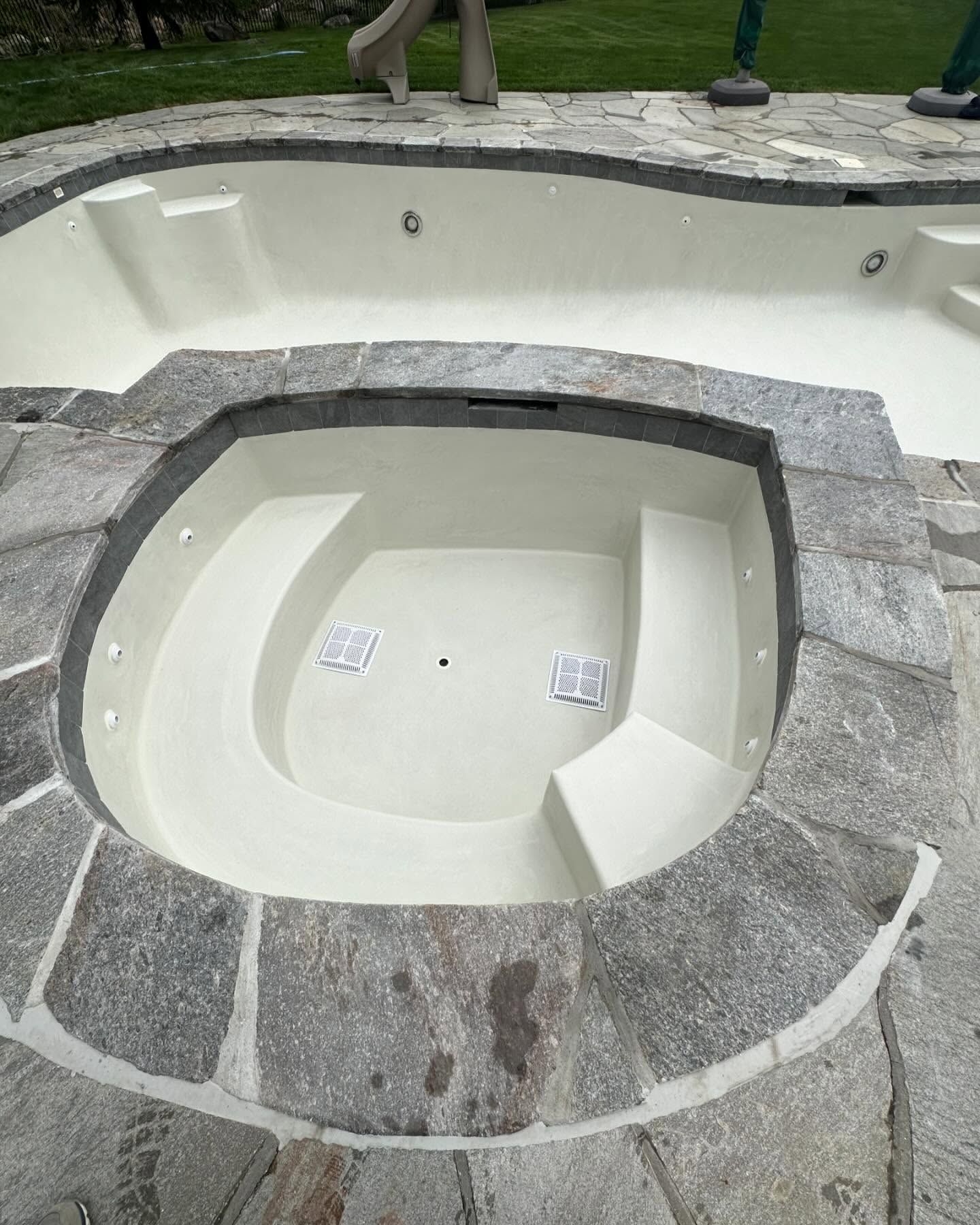 A swimming pool with a jacuzzi in the middle of it