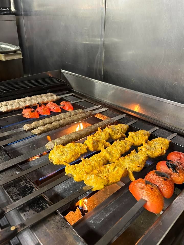 A bunch of food is cooking on a grill in a kitchen.