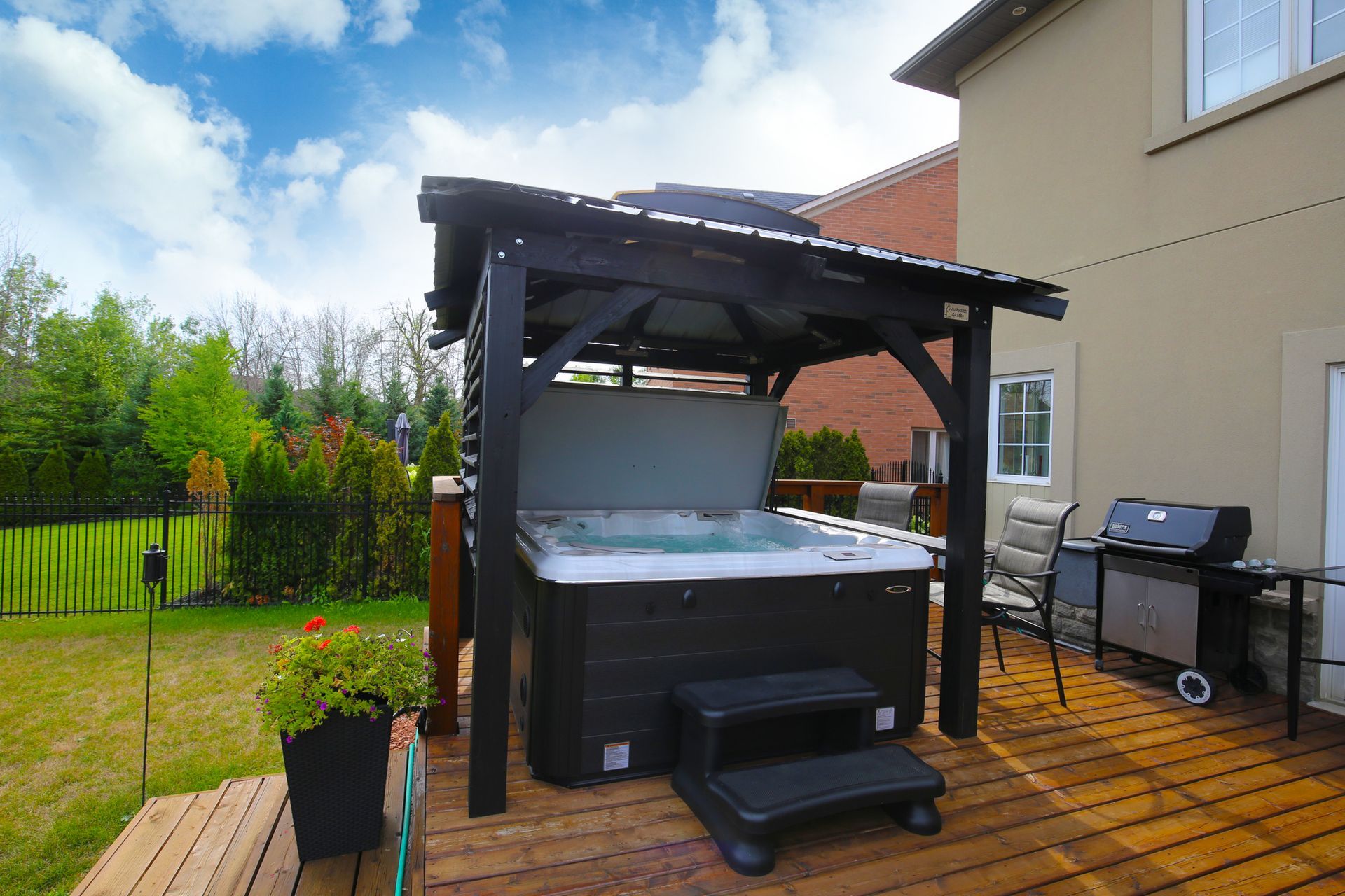 A hot tub is sitting under a gazebo on a wooden deck.