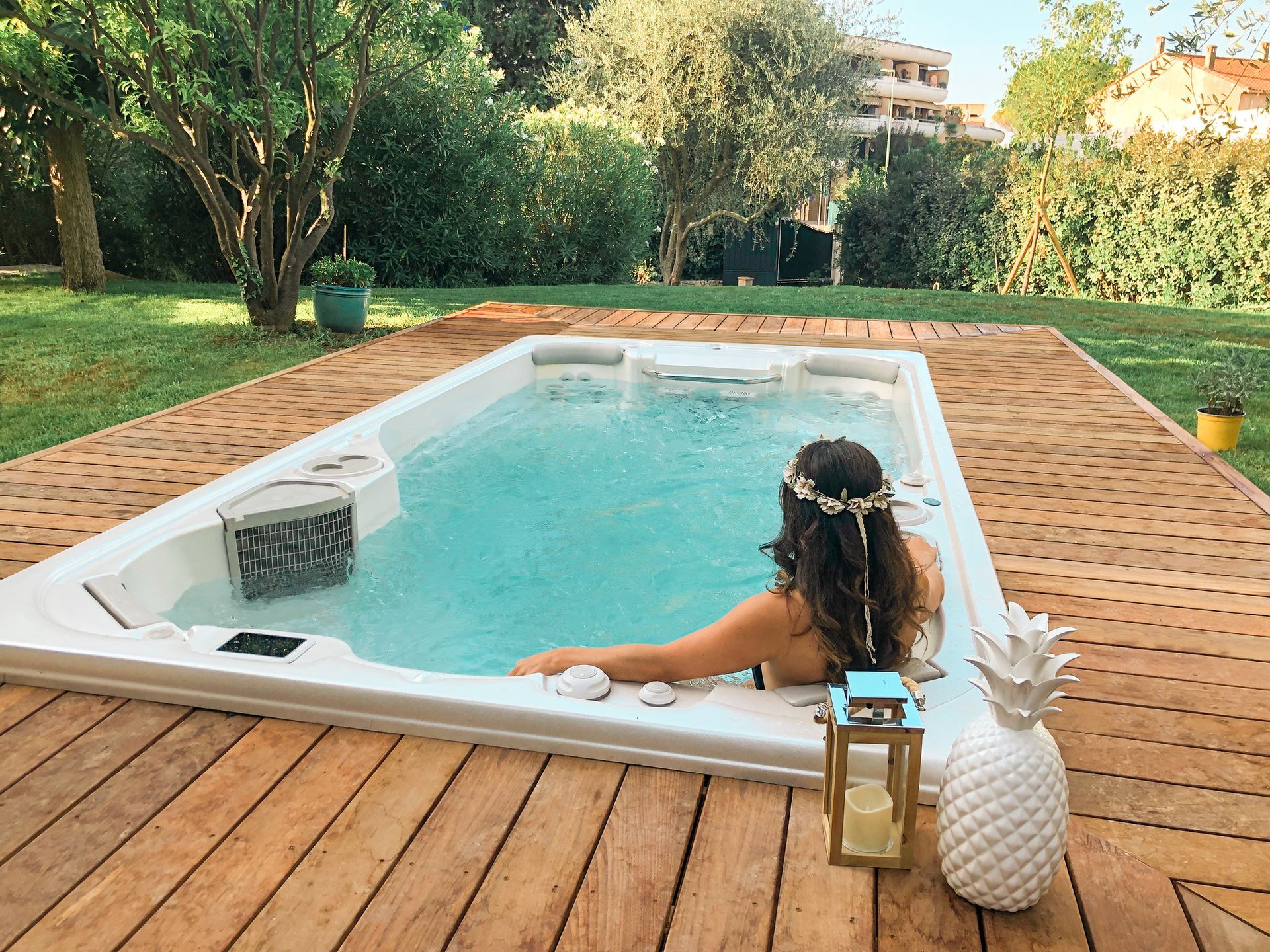 A woman is sitting in a hot tub on a wooden deck.