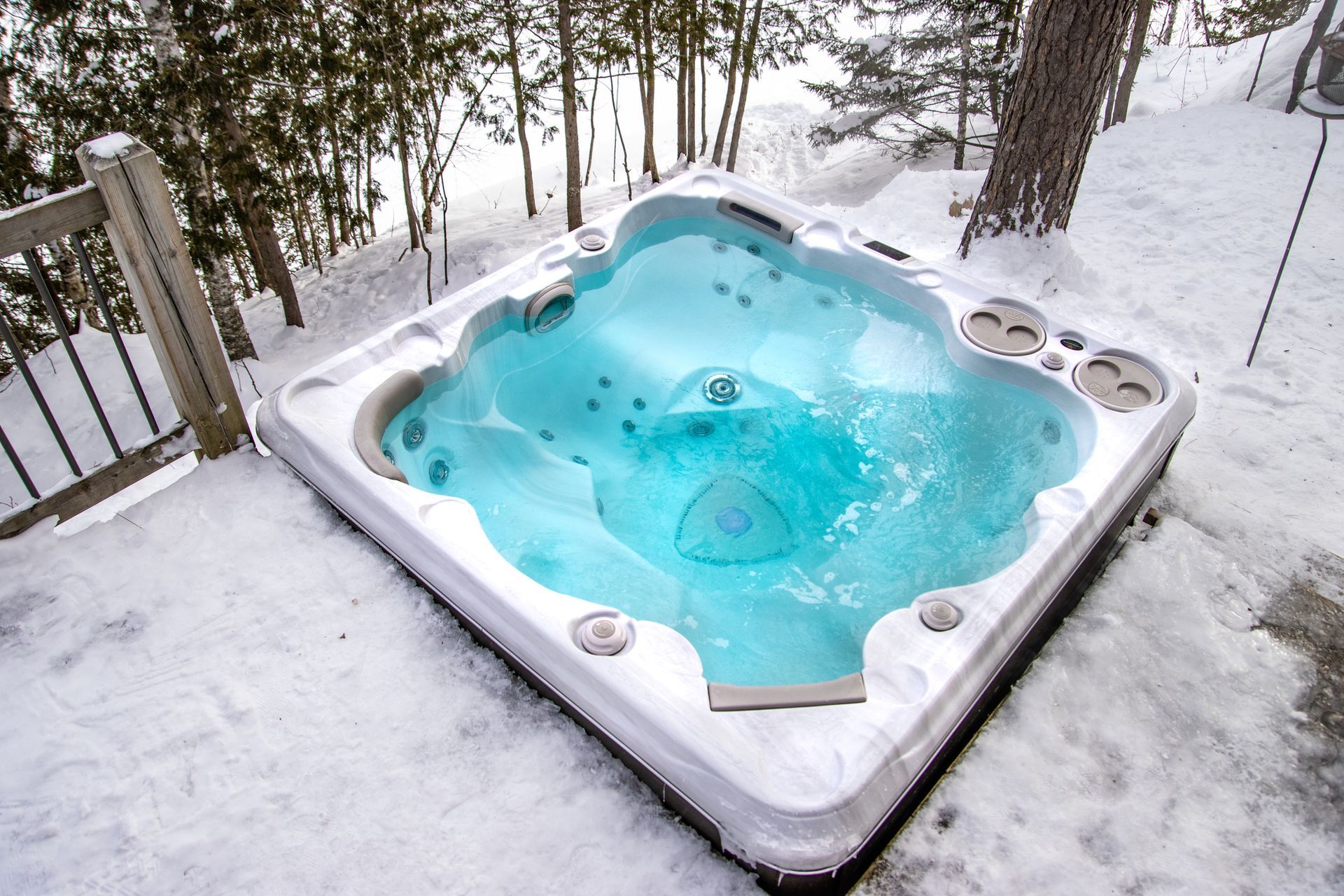 A hot tub is sitting in the snow on a deck.