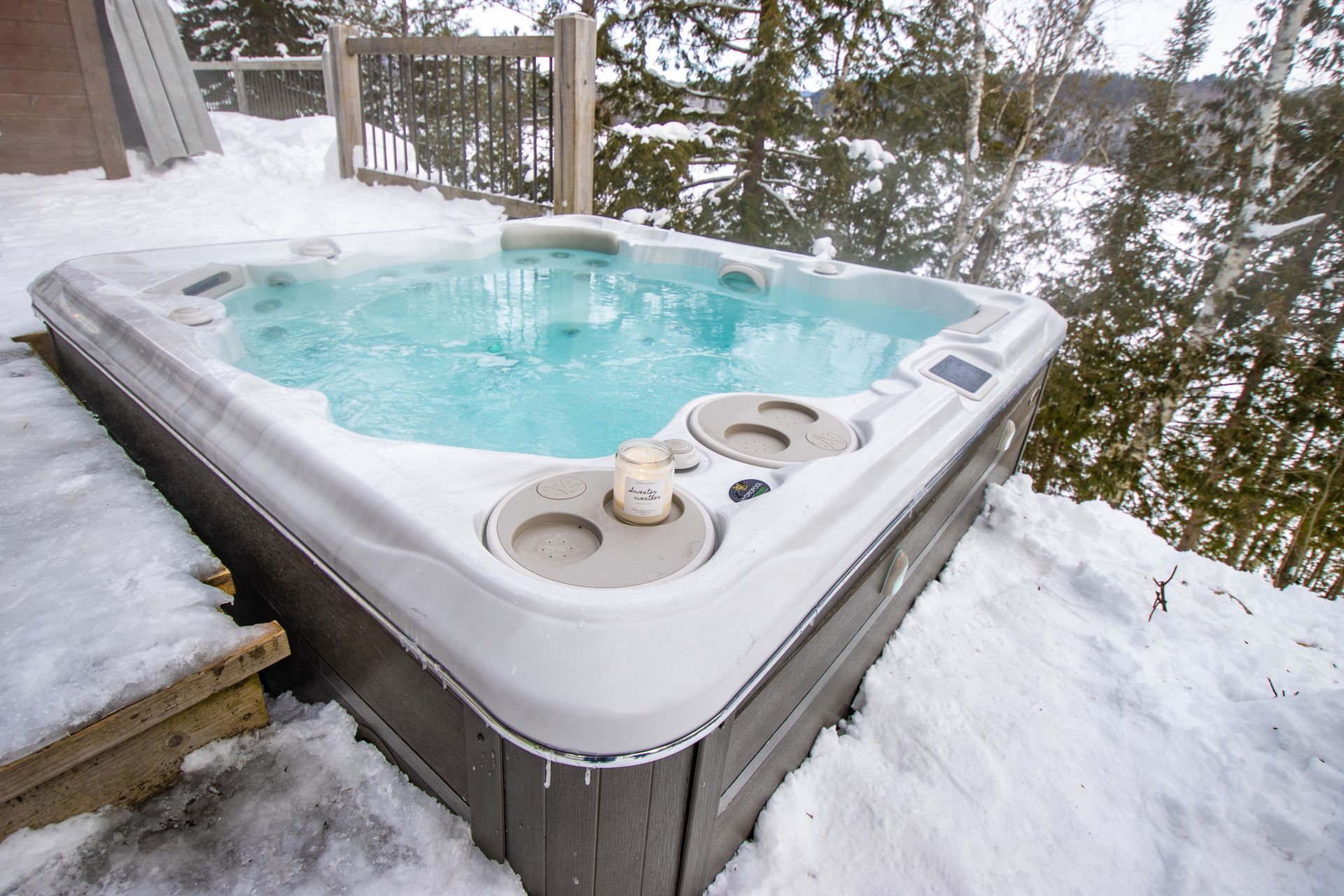 A hot tub is sitting in the snow on a deck.