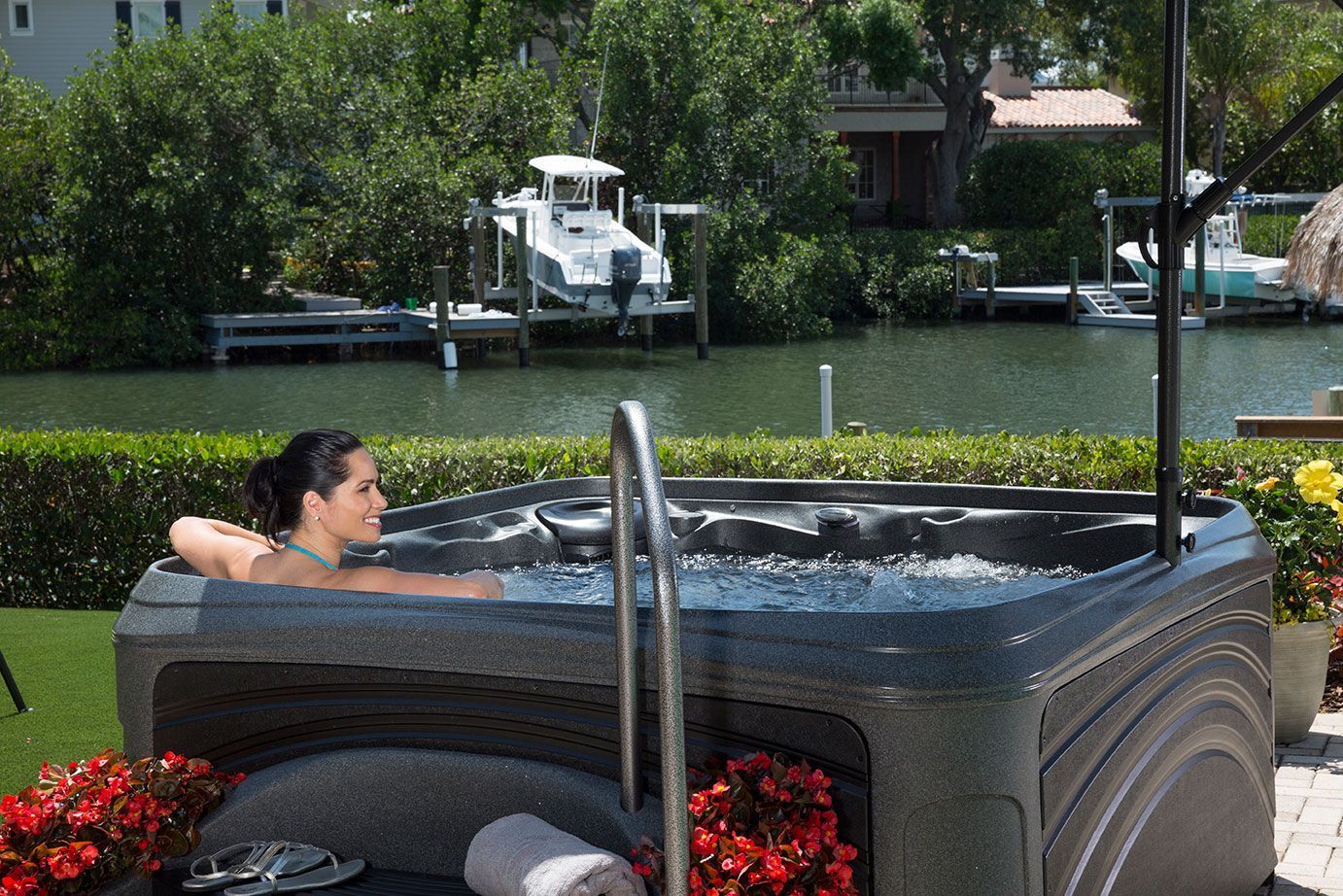 A woman is sitting in a hot tub next to a body of water.