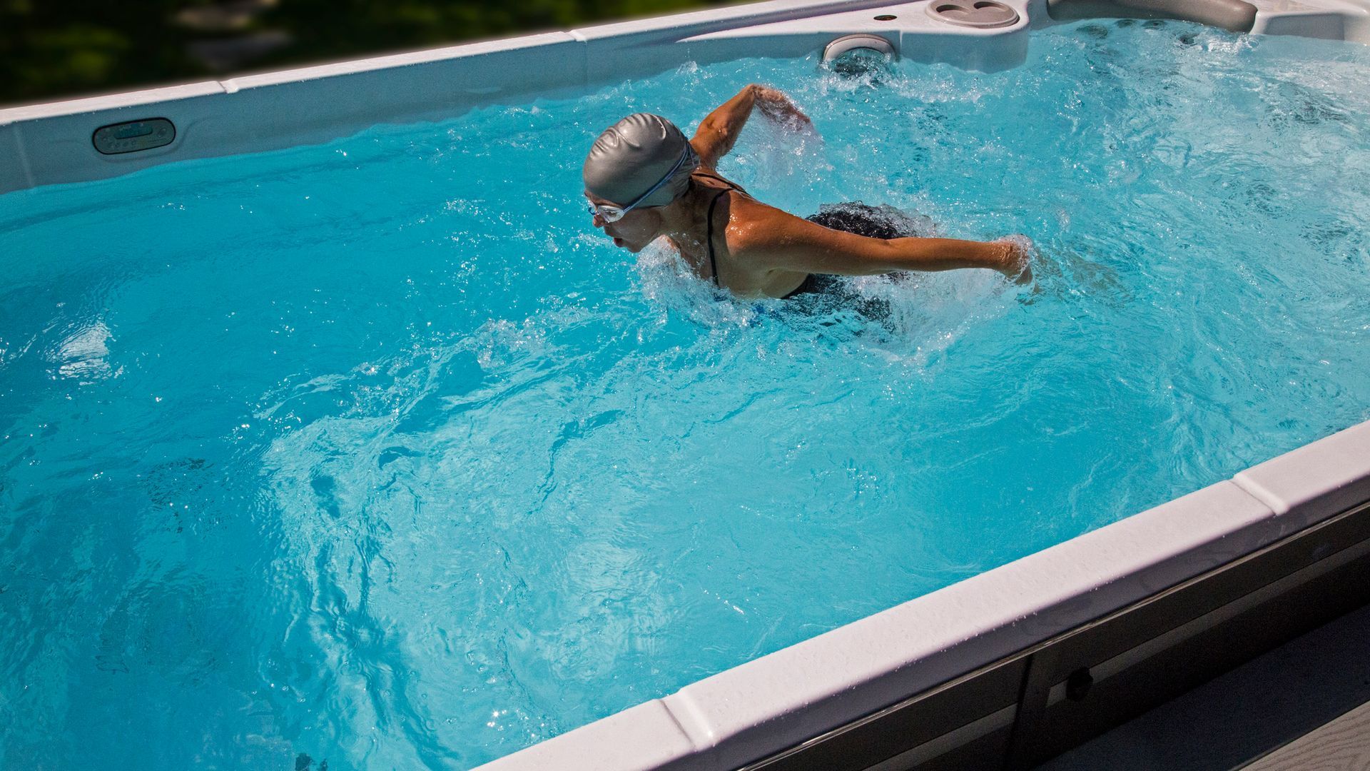 A woman is swimming in a large swimming pool.