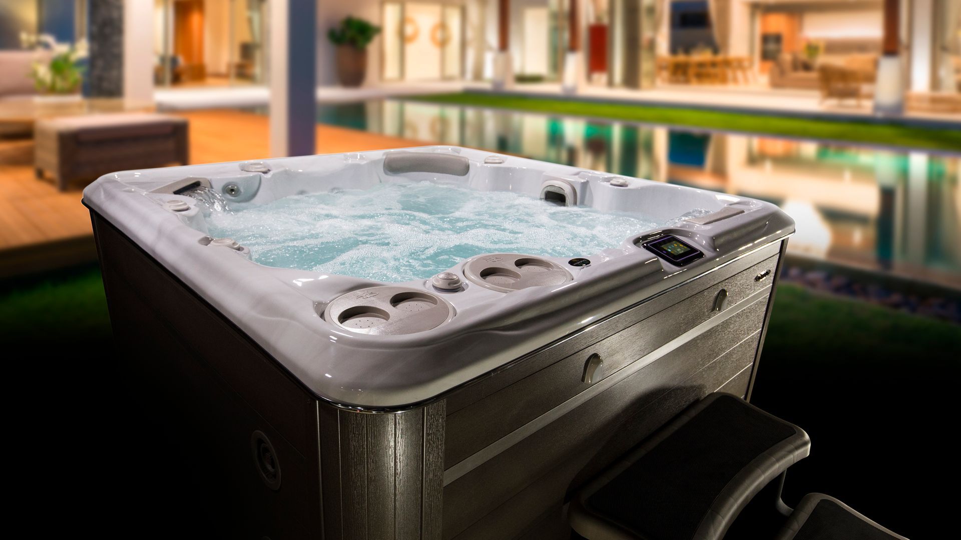 A hot tub is sitting next to a swimming pool in front of a house.