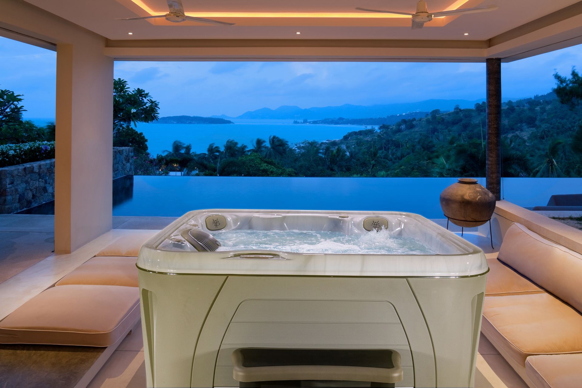 There is a hot tub in the middle of the room with a view of the ocean.