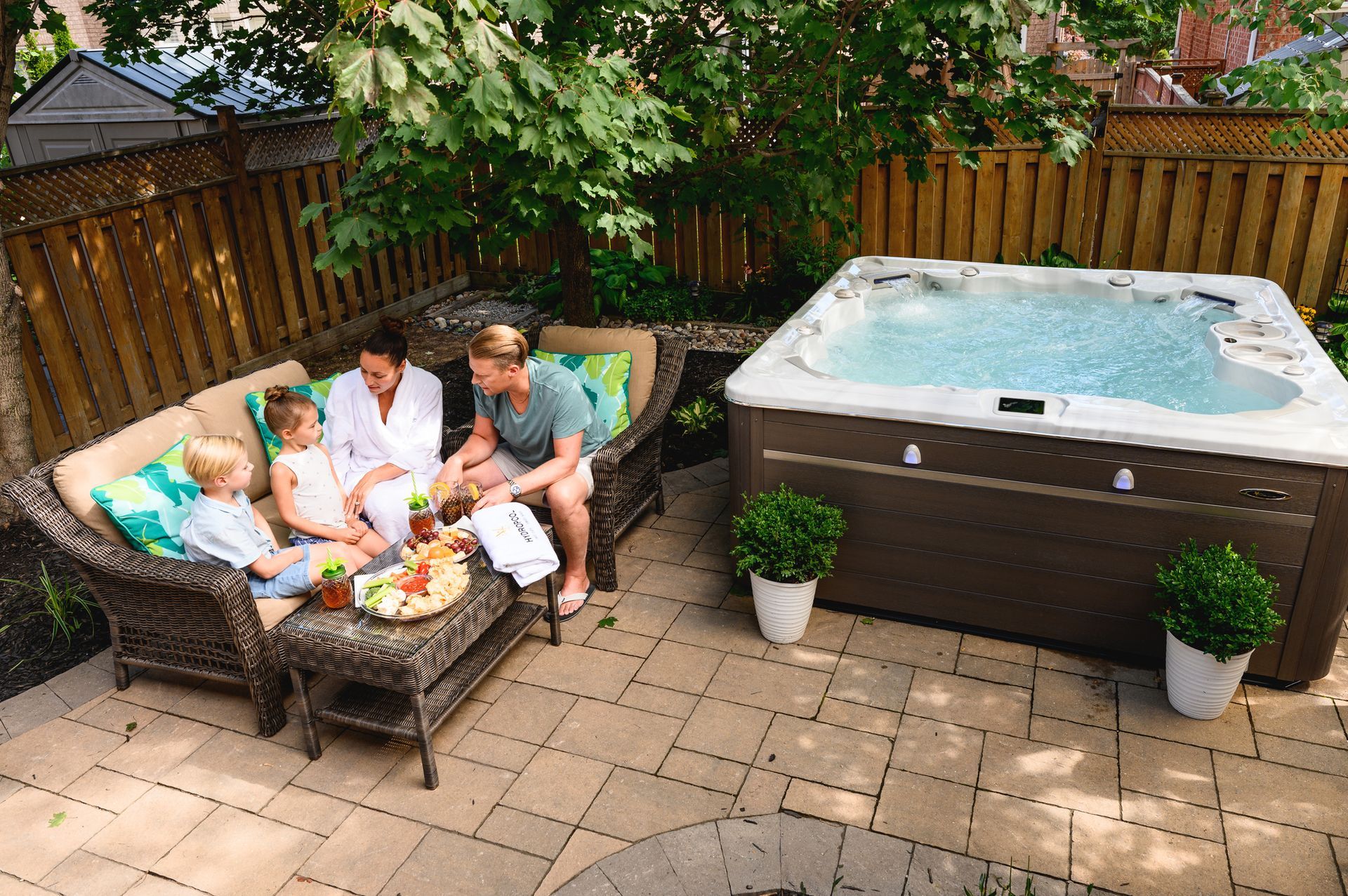 A family is sitting on a patio next to a hot tub.