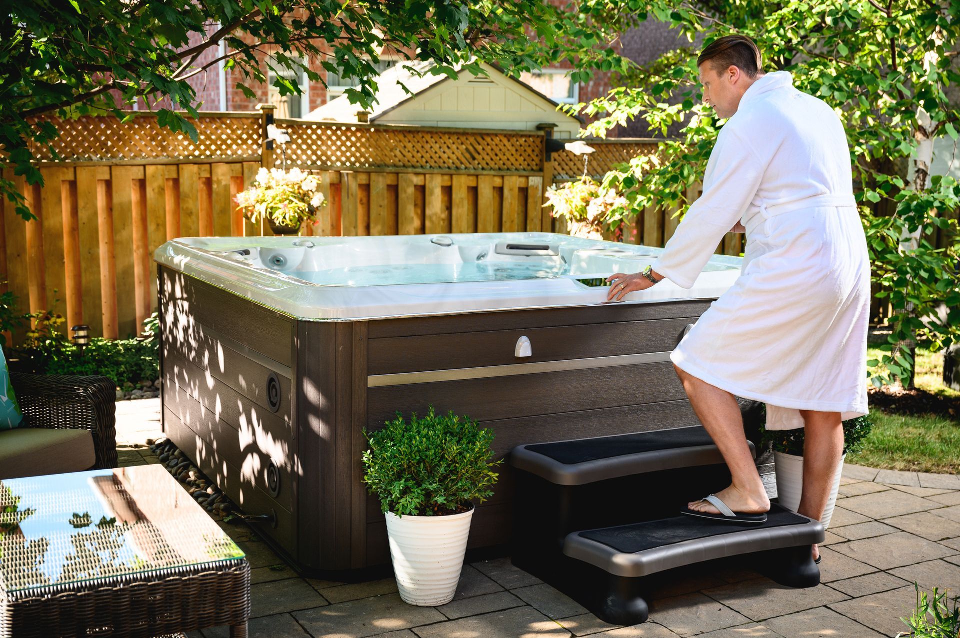 A man in a bathrobe is standing next to a hot tub.