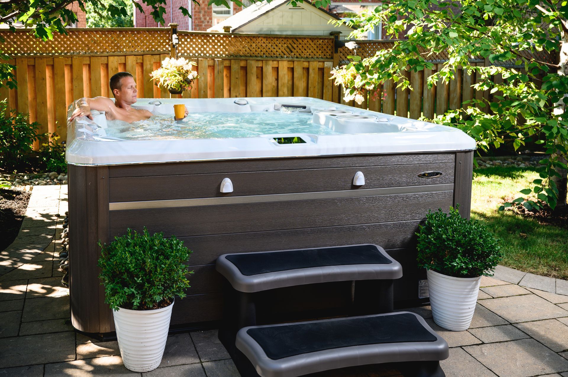 A man is sitting in a hot tub in a backyard