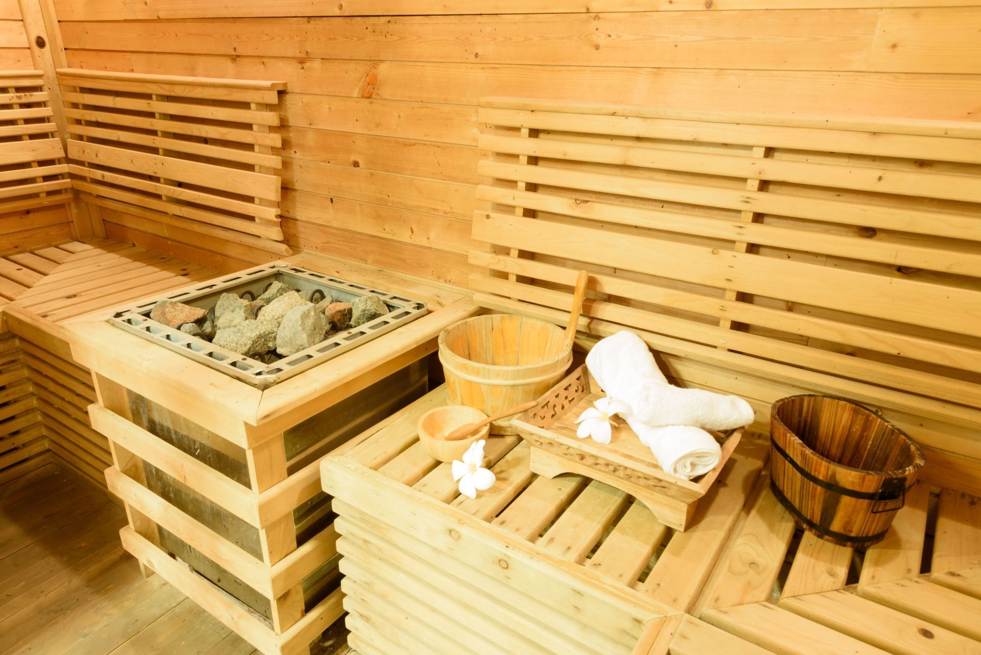 A wooden sauna with a bucket and towels on the bench.