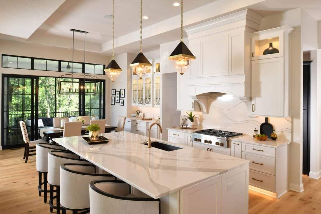 Modern open-concept kitchen with white cabinetry, marble island, and black pendant lights