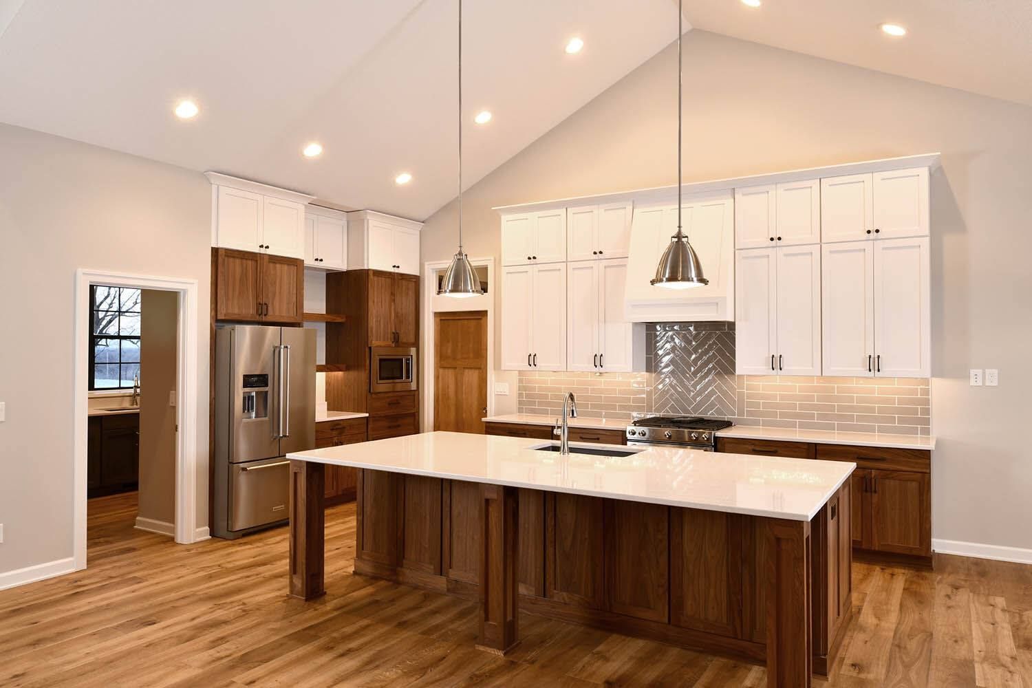 Modern kitchen with white cabinets, wood floors, stainless appliances, and a large island under pendant lights
