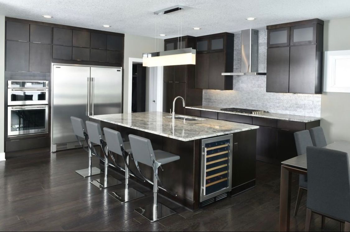 Modern kitchen with dark cabinets, stainless steel appliances, and a large island with bar stools.