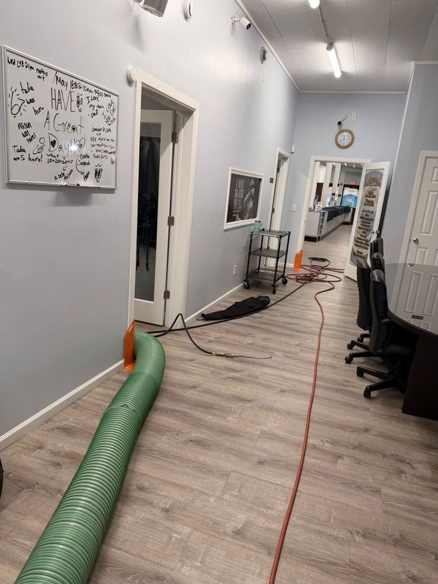 Long hallway with work equipment, cords, and a green air duct on the floor