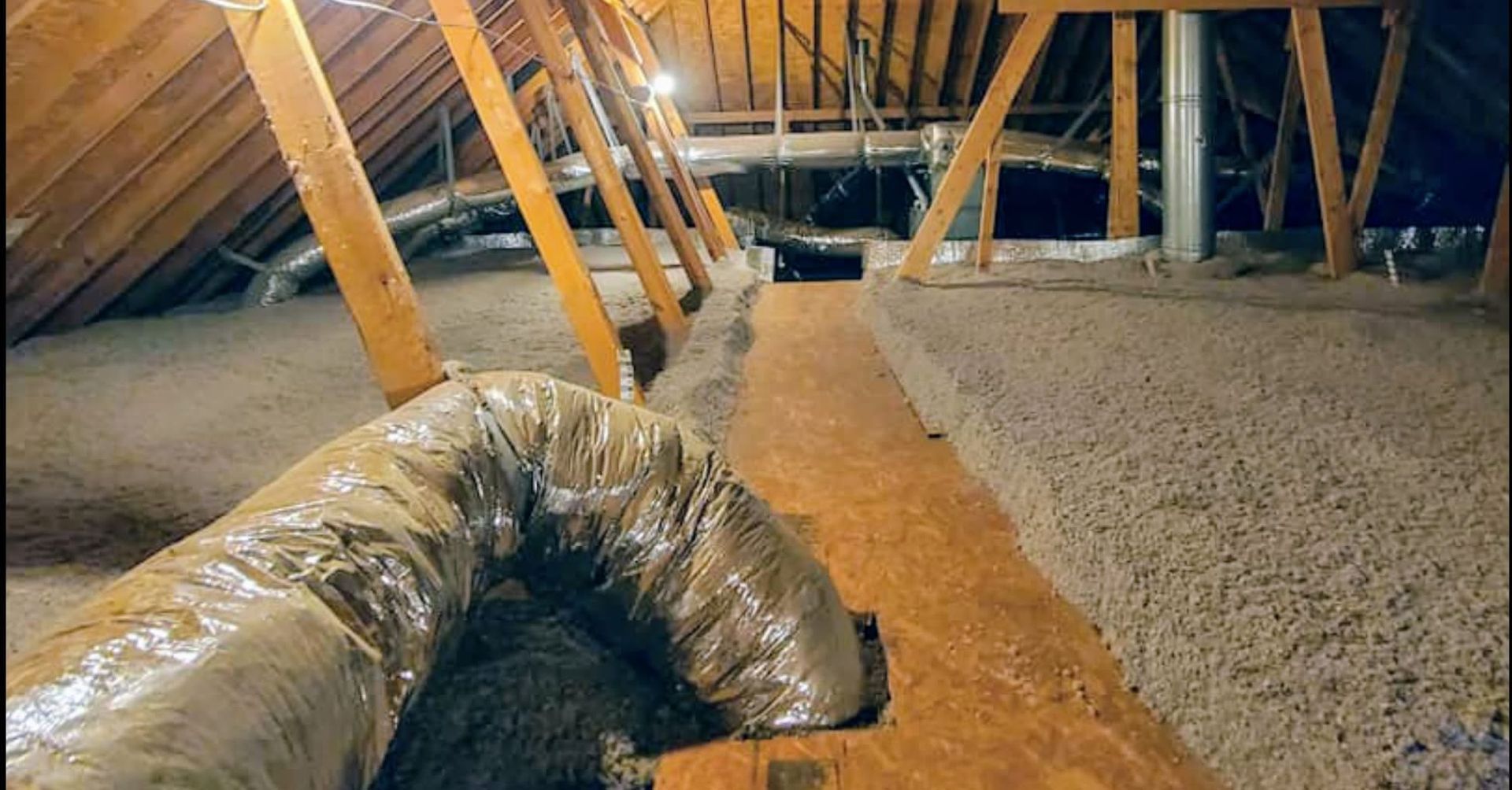Attic insulation works with flexible ducting and spray foam along rafters and floor joists