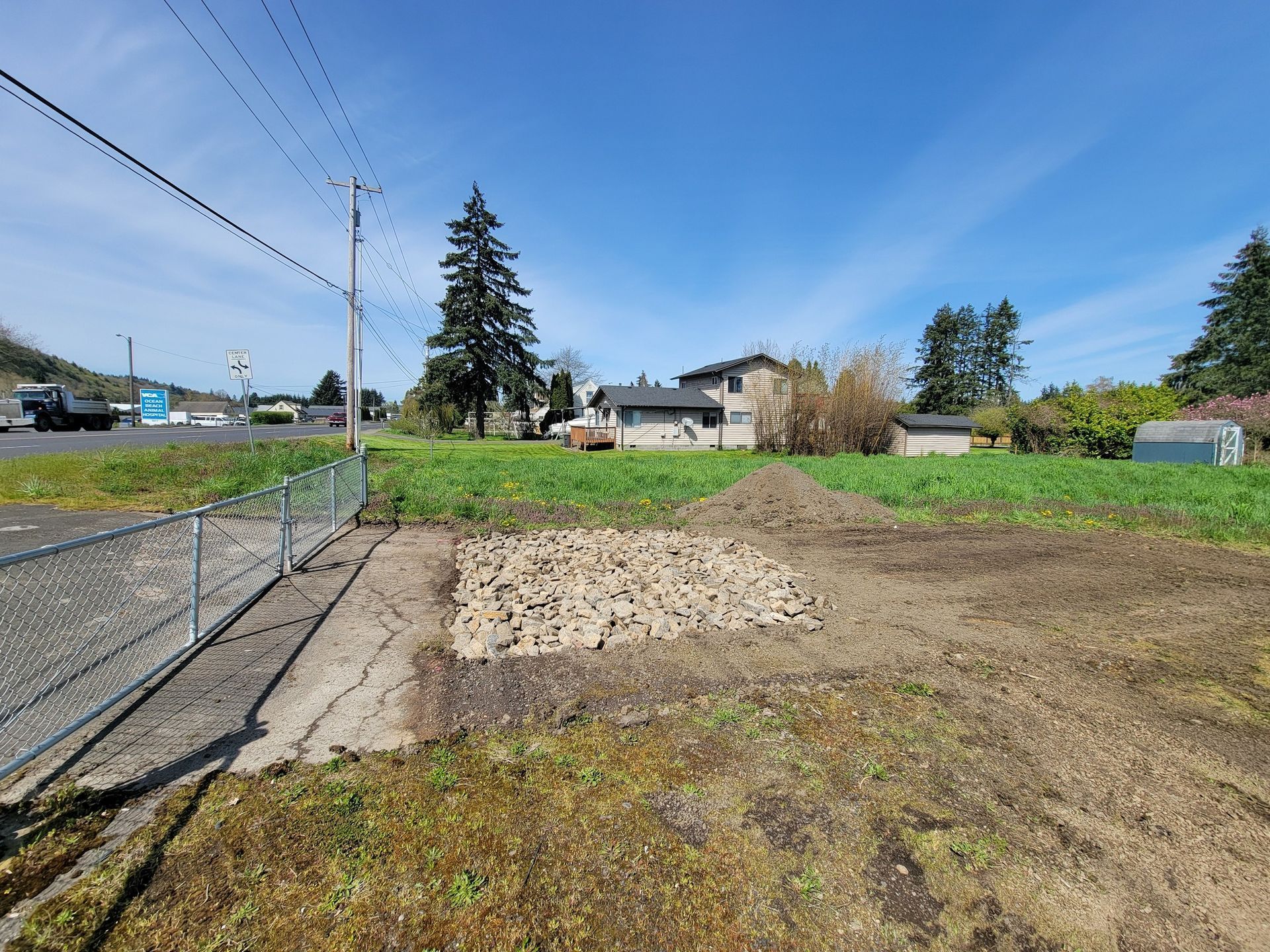 A large empty field with a fence and a house in the background.