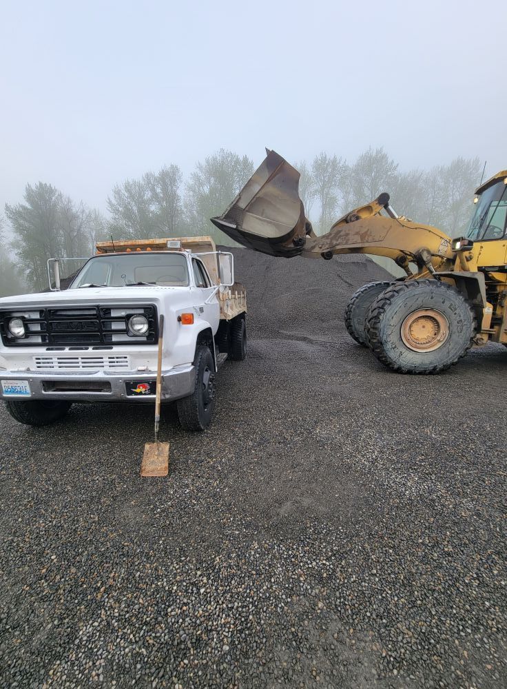 A dump truck is being loaded with gravel by a bulldozer.