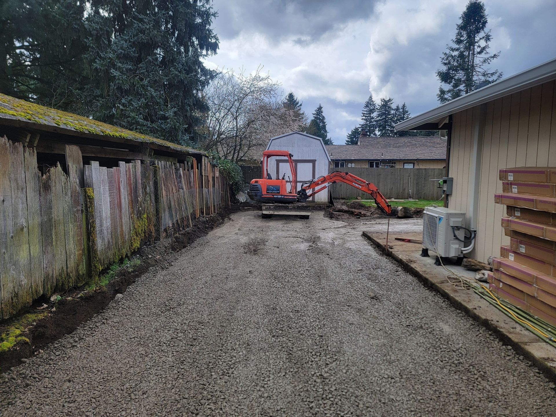 A gravel driveway leading to a building with a bulldozer in the background.