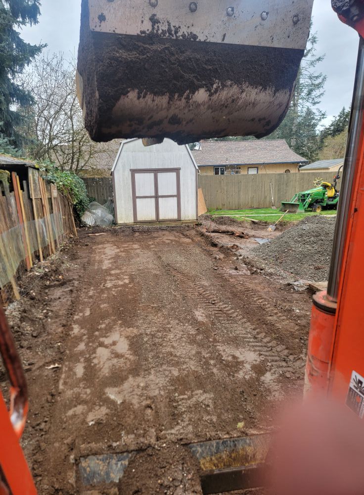 A bulldozer is digging a dirt road in front of a garage.