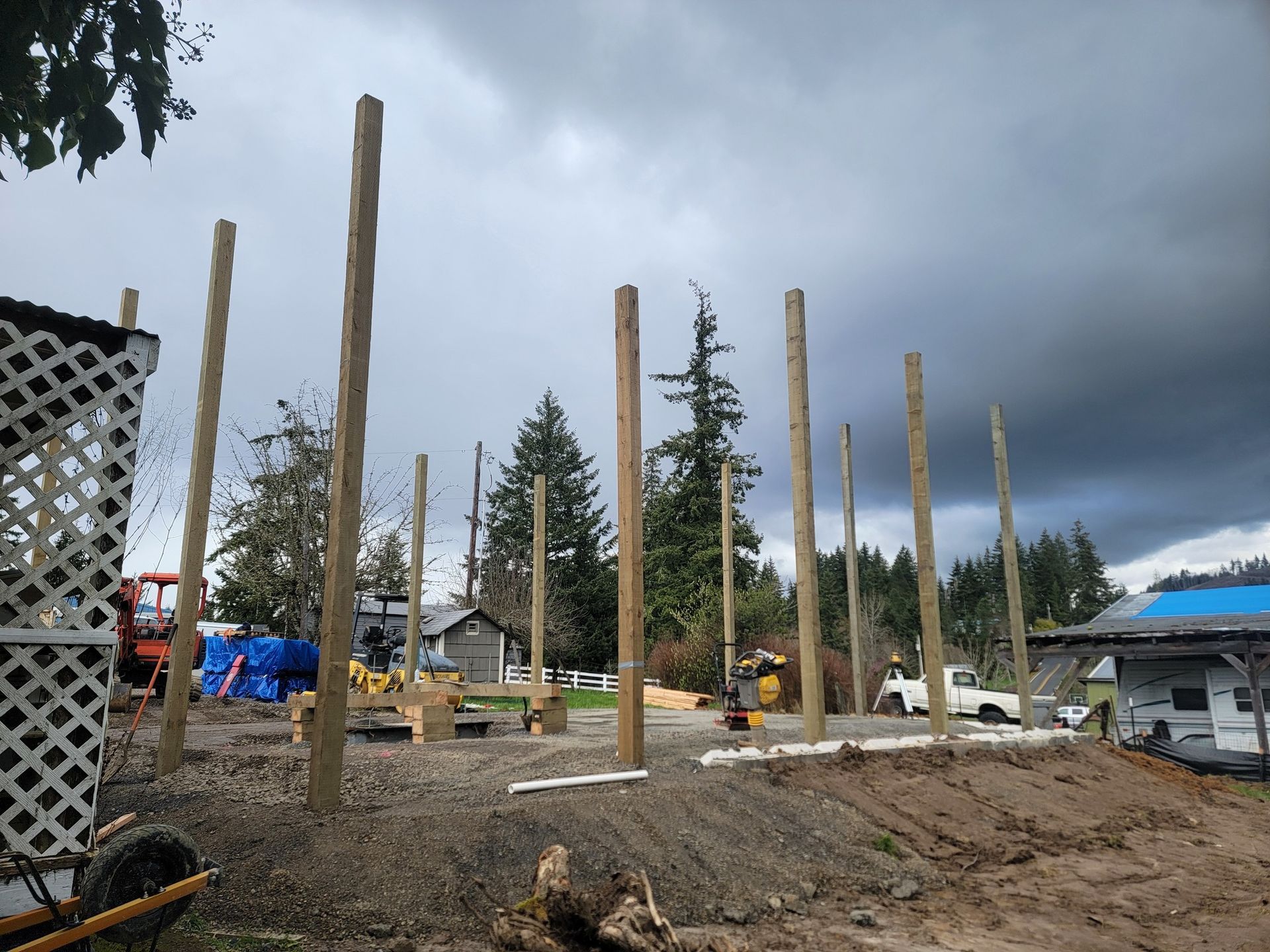 A row of wooden poles are lined up in the dirt in front of a cloudy sky