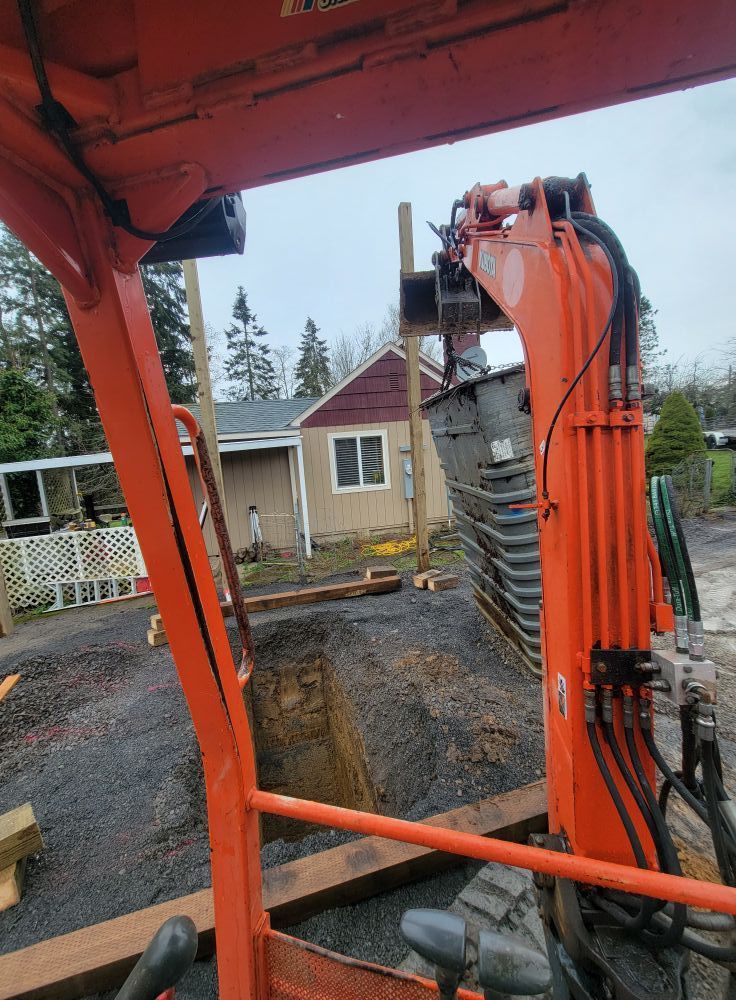 An orange excavator is digging a hole in the ground in front of a house.