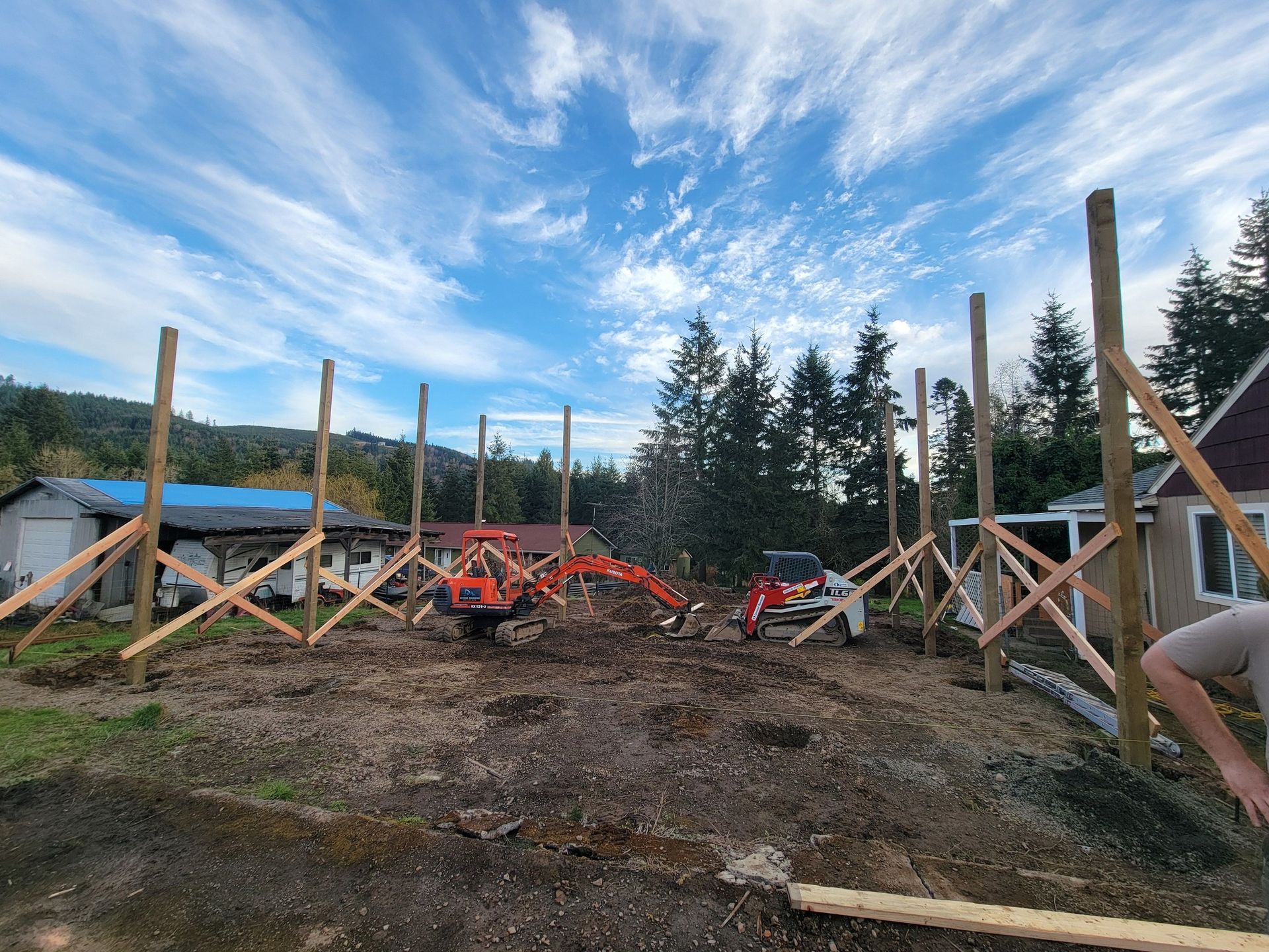 A construction site with a tractor and a house in the background.
