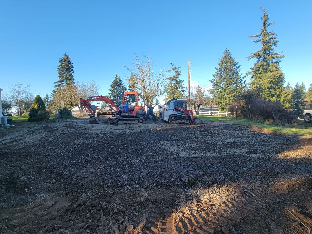 A group of construction vehicles are parked in a dirt lot.