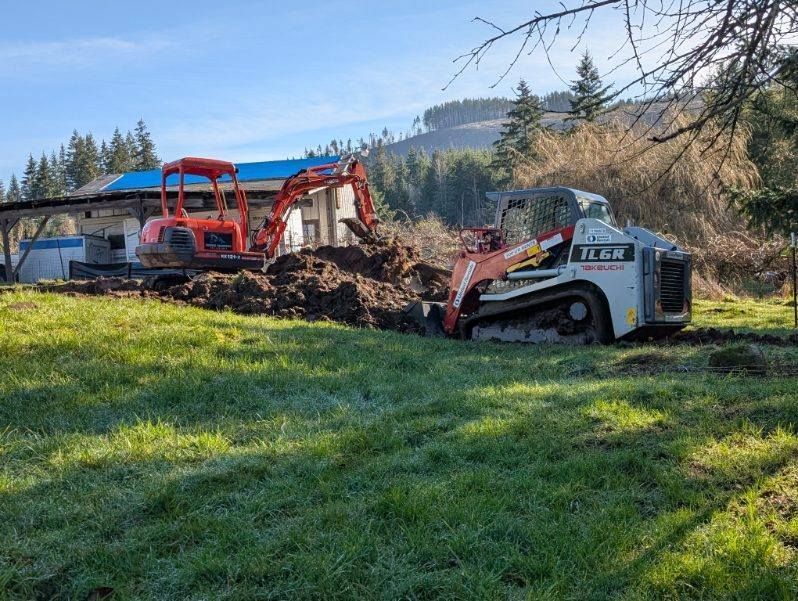 A bulldozer is digging a hole in a grassy field.