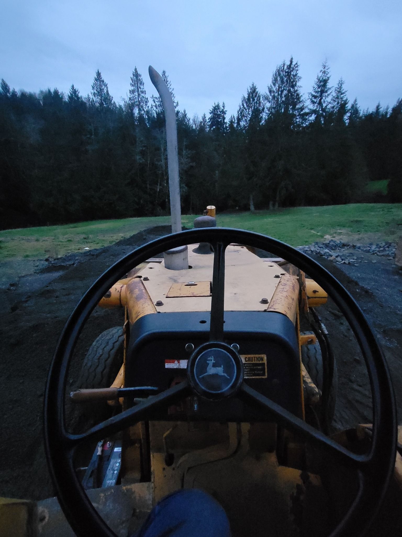 A john deere tractor is parked in a field with trees in the background