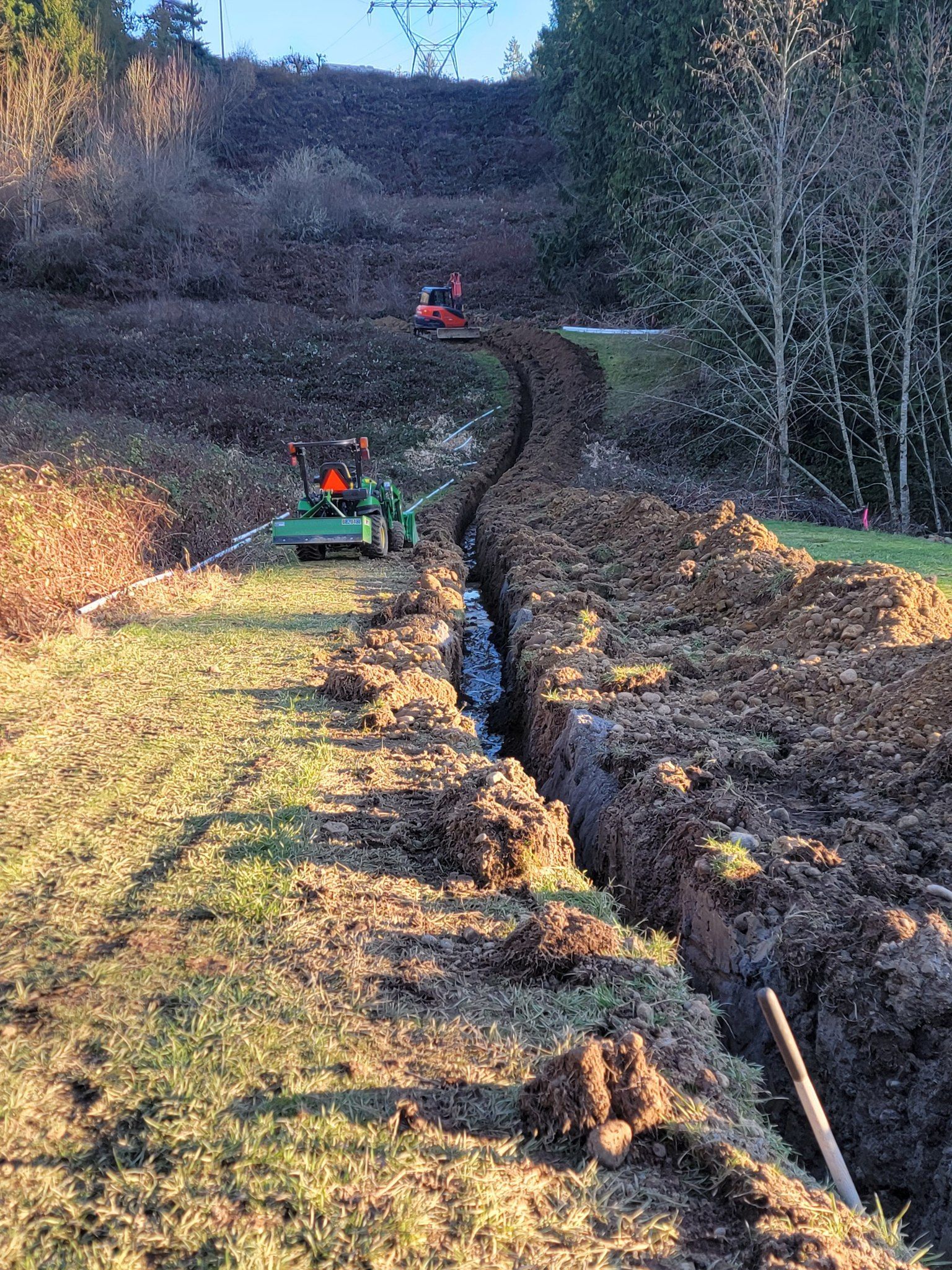 A tractor is digging a trench in a field.