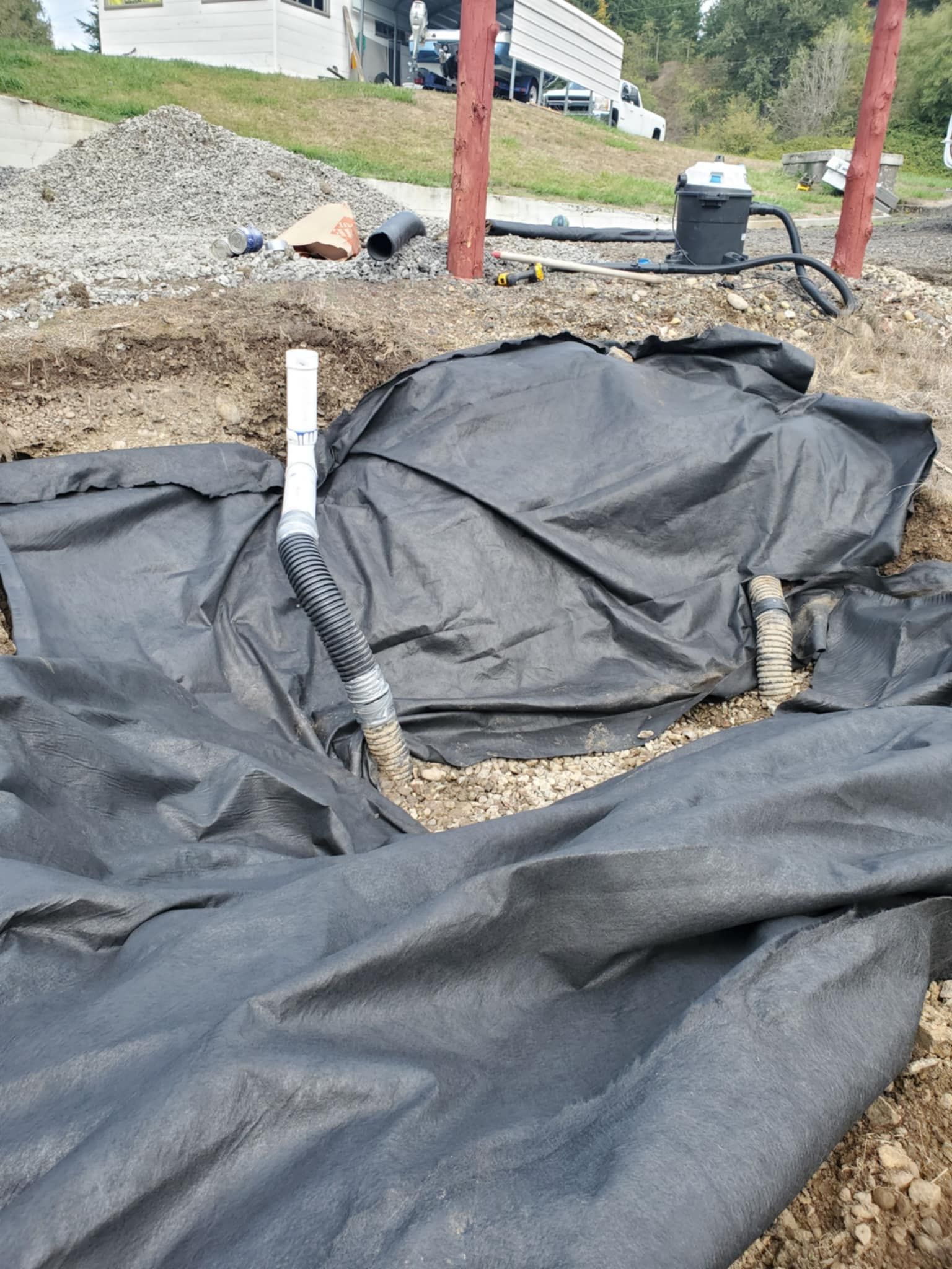 A large piece of black tarp is laying on top of a pile of dirt.