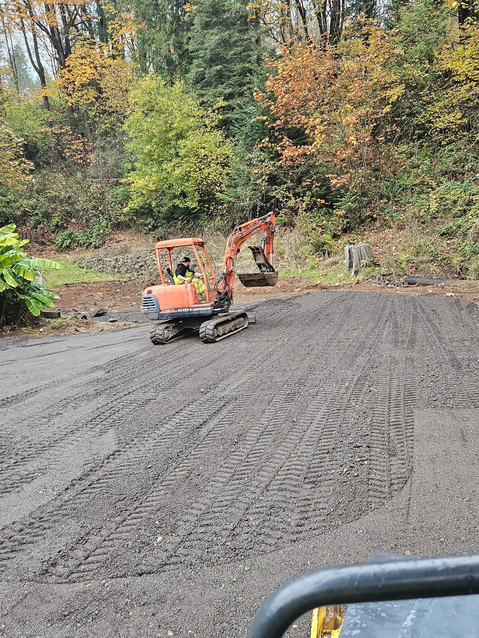 A small orange excavator is sitting in the middle of a dirt field.