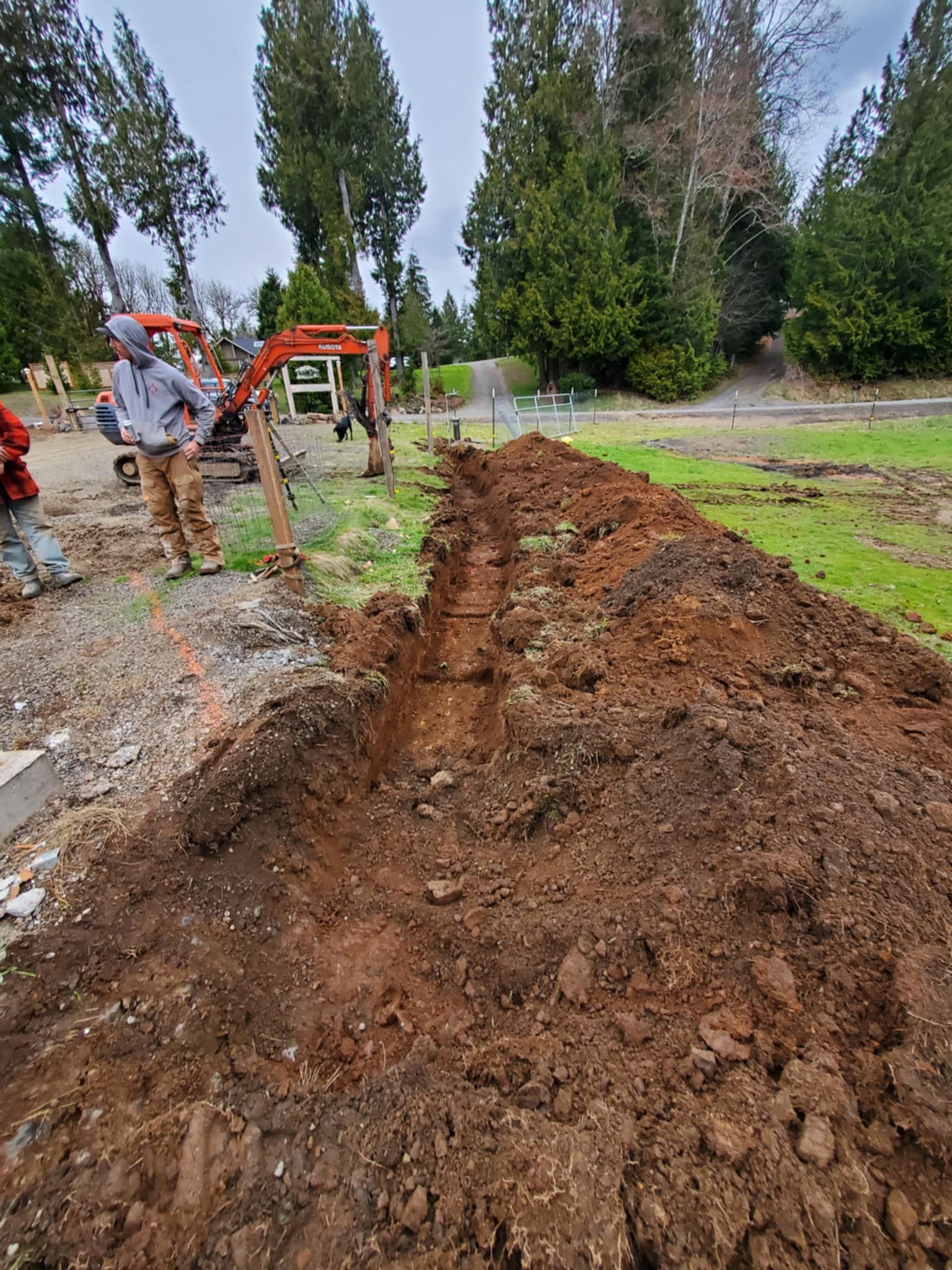 A man is standing next to a pile of dirt in a field.