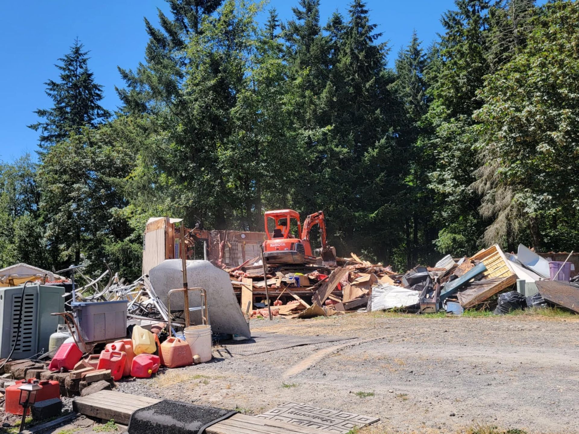 A bulldozer is demolishing a house in the middle of a forest.