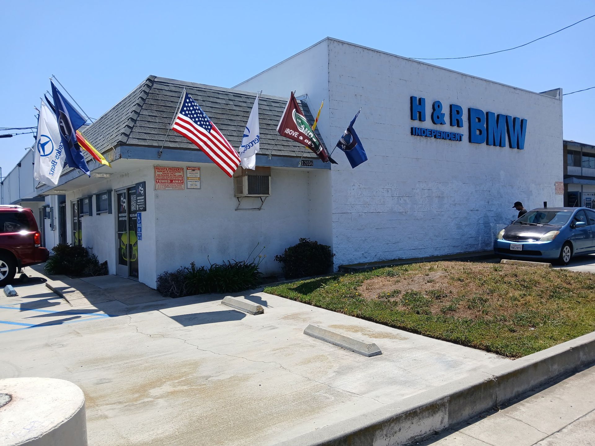Exterior of H&R Block office with American flags and parked cars on a sunny day