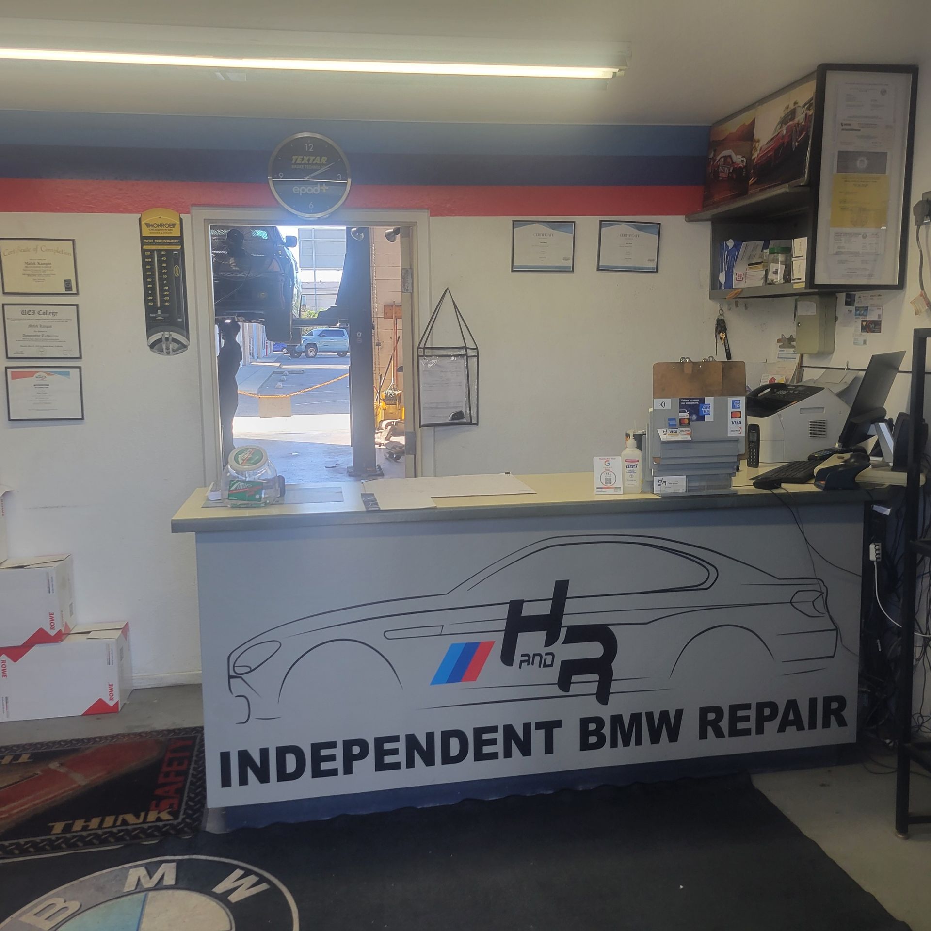 Independent BMW repair shop front desk with counter, tools, and signs on the walls
