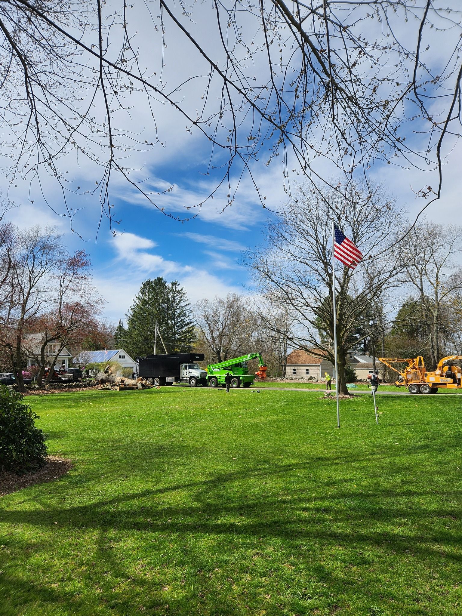 A green tractor is parked in a grassy field next to a flag pole.