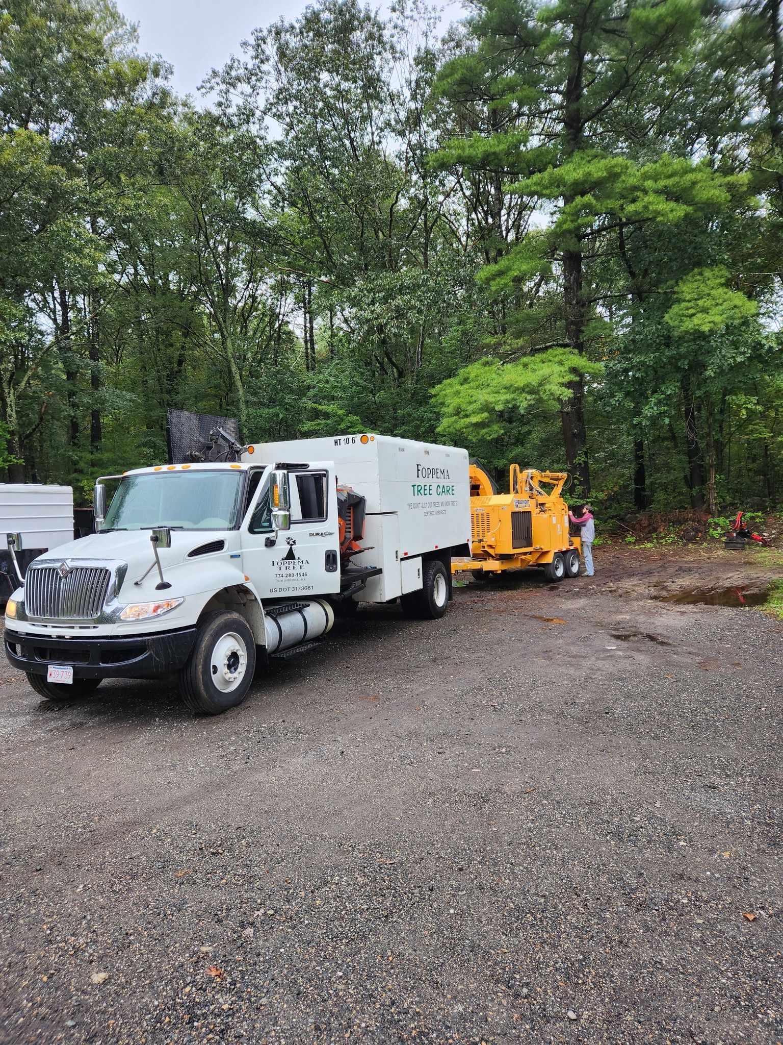 A white truck is parked next to a yellow truck in a gravel lot.