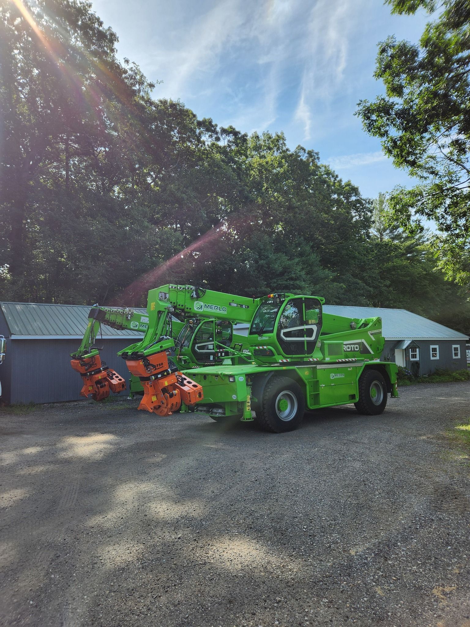 A green crane is parked in a gravel lot in front of a building.