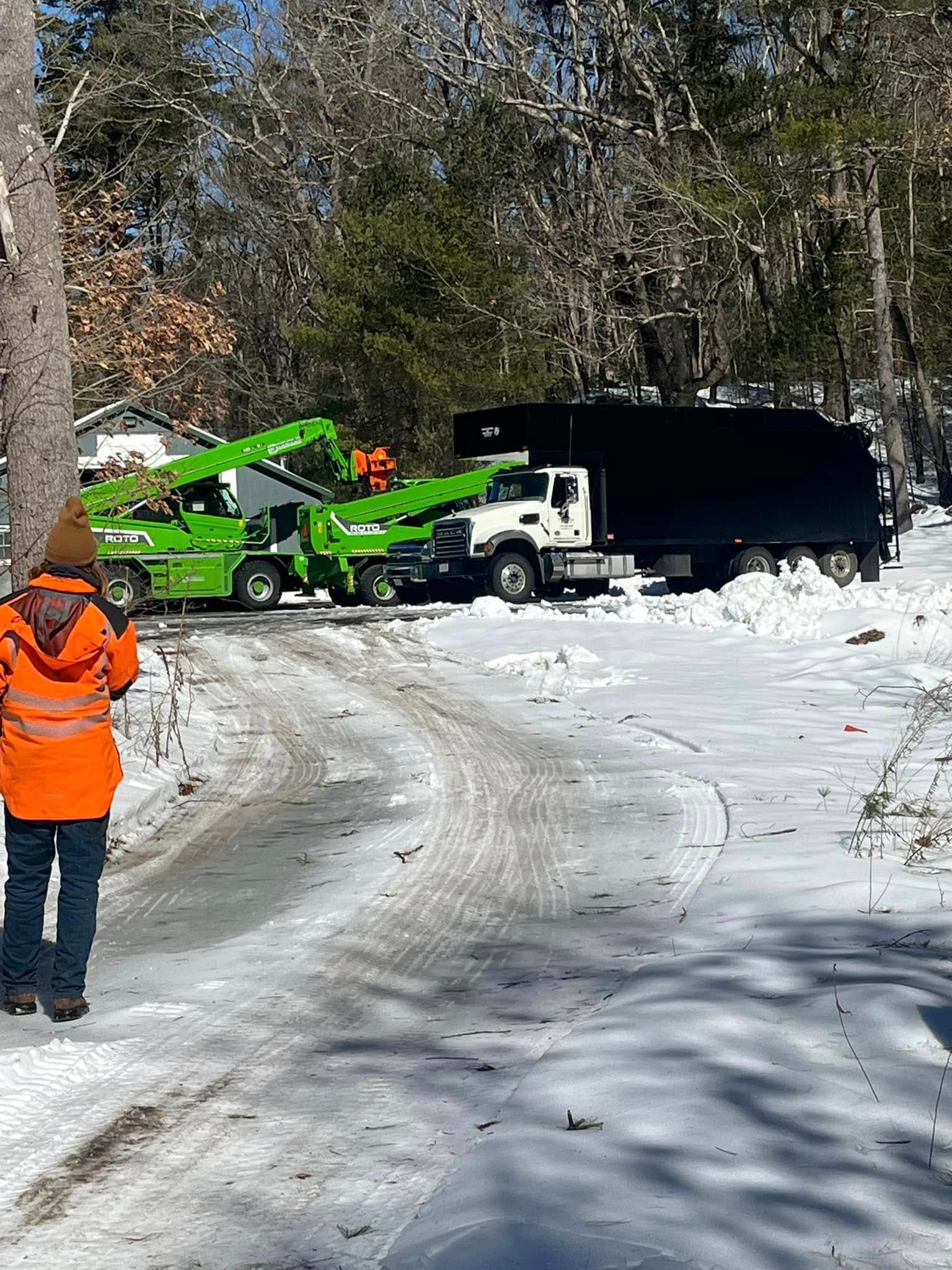 A man in an orange jacket is walking down a snowy road.