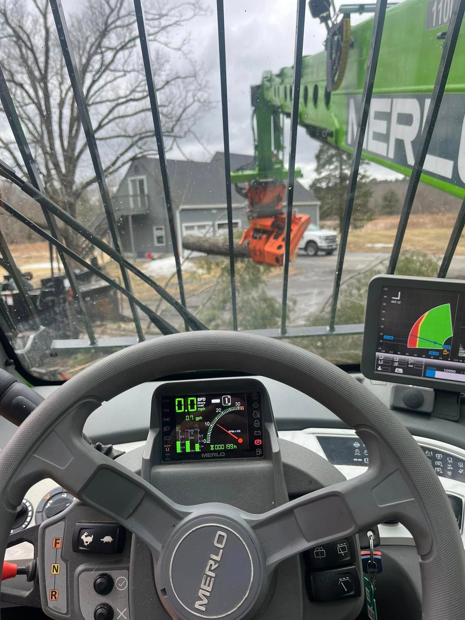 A steering wheel and dashboard of a tractor with a crane in the background.