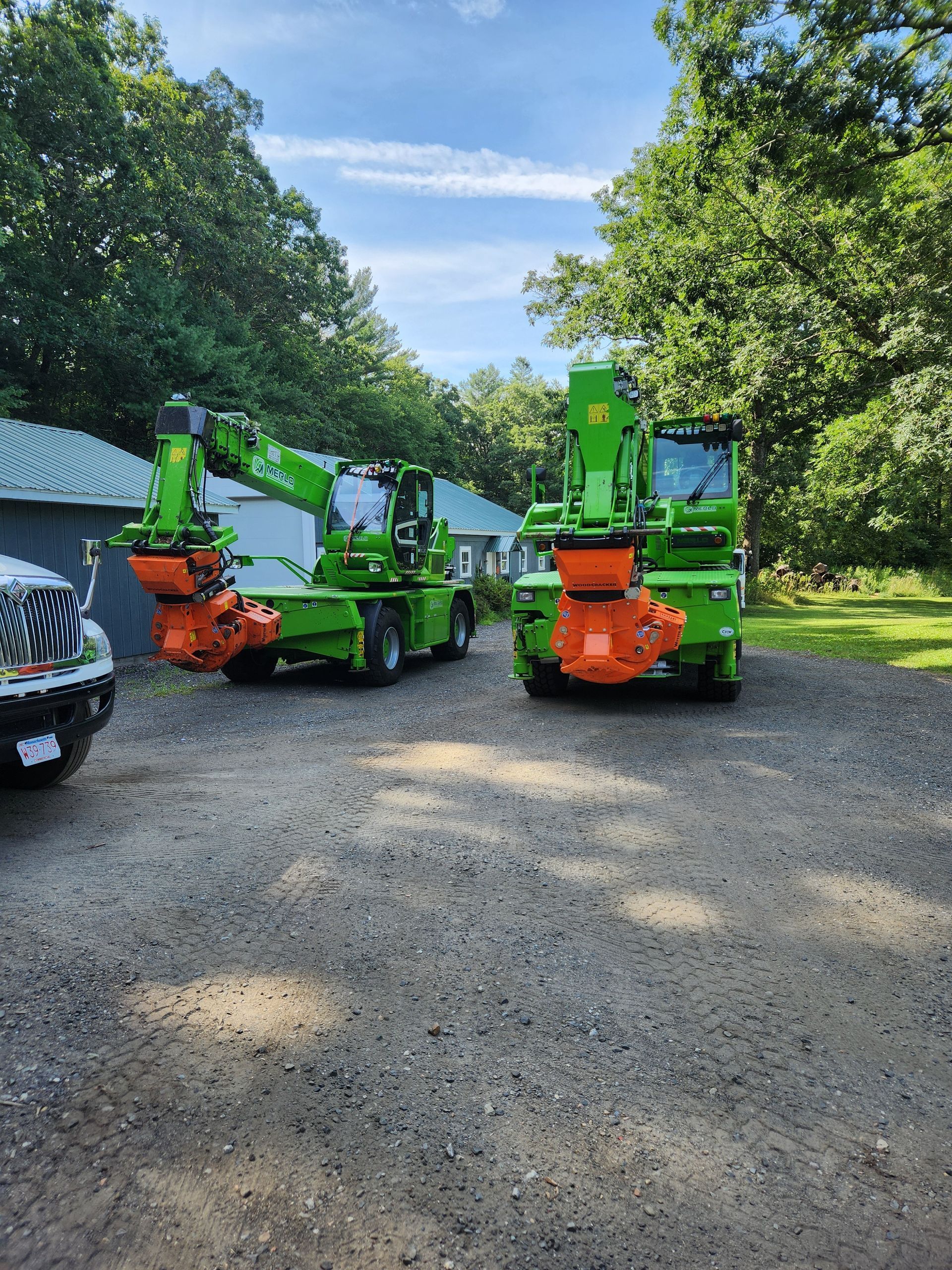 Two green tractors are parked next to each other in a gravel driveway.